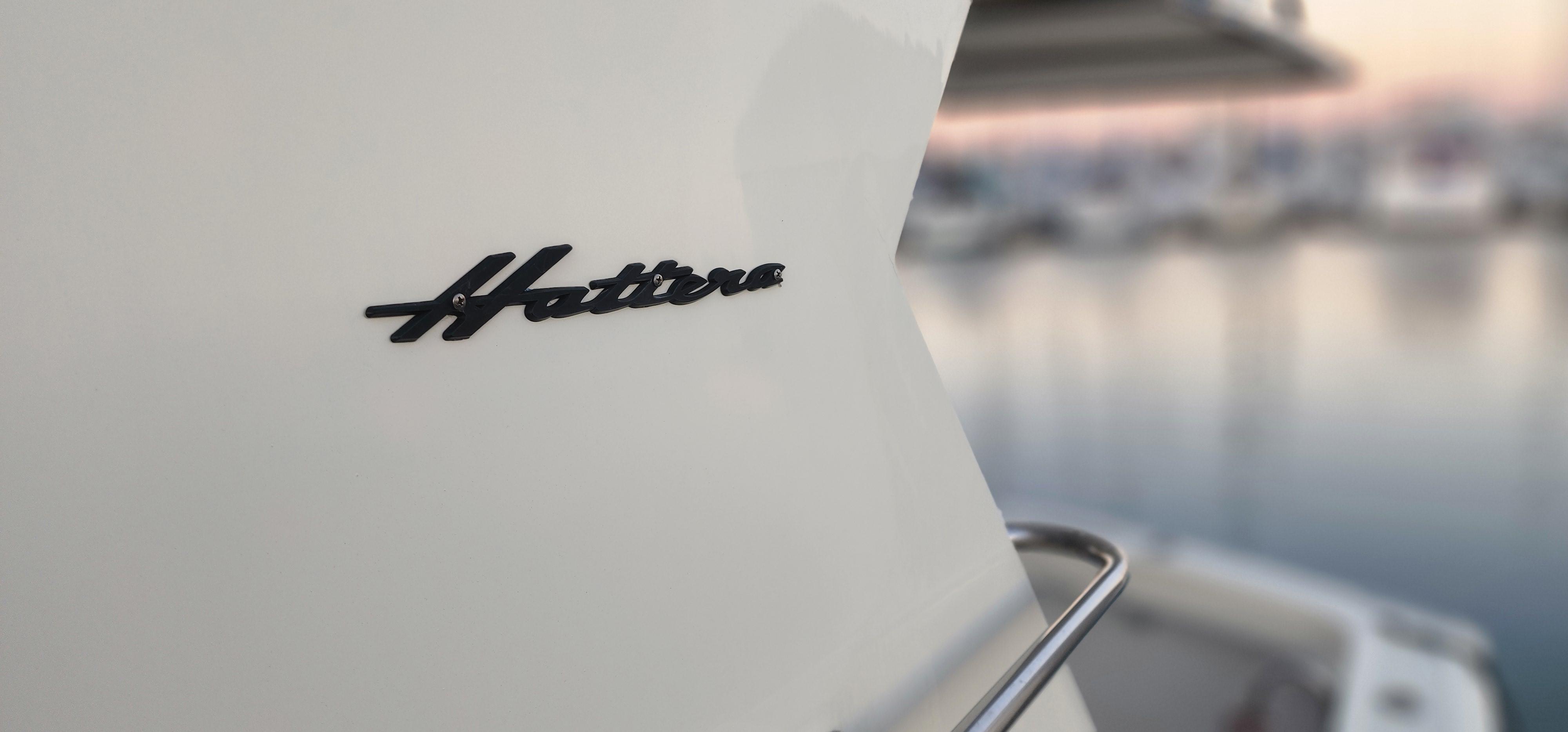 1978 Hatteras Sportfish boat with logo, docked at marina during sunset.