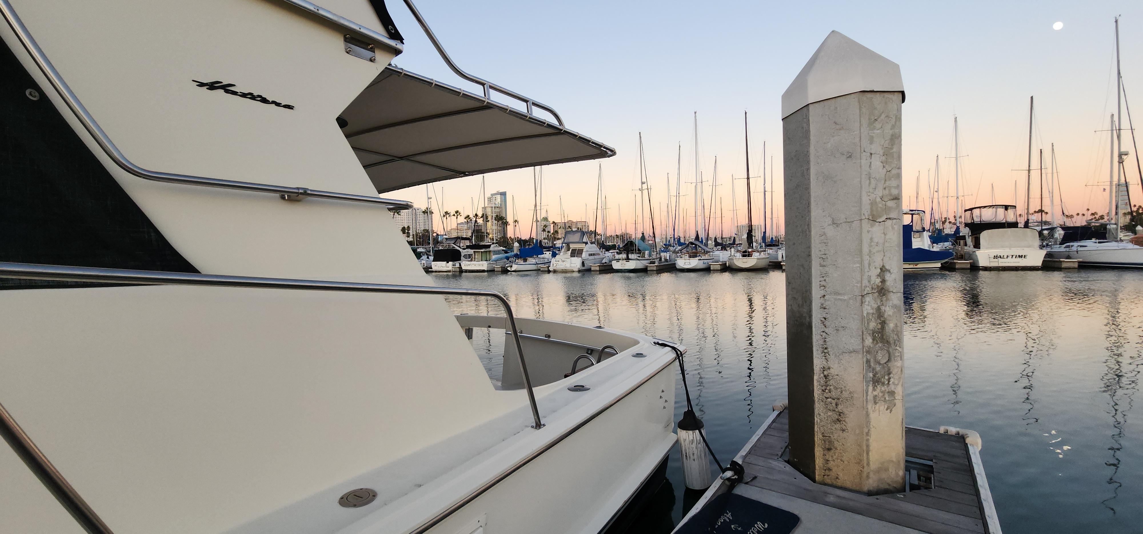 1978 Hatteras Sportfish yacht docked at marina during sunset, surrounded by sailboats.