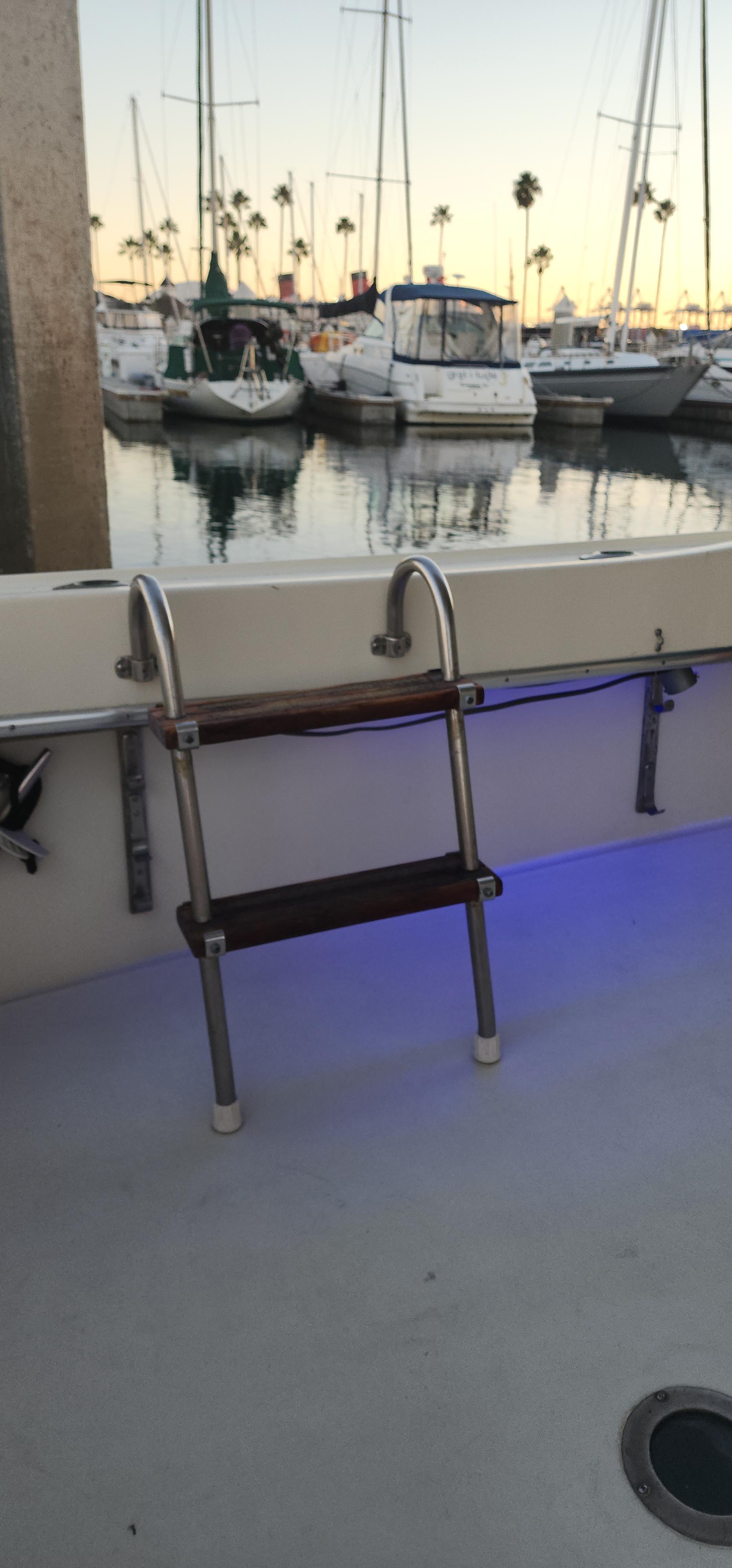 1978 Hatteras Sportfish boat with ladder, docked at marina during sunset.