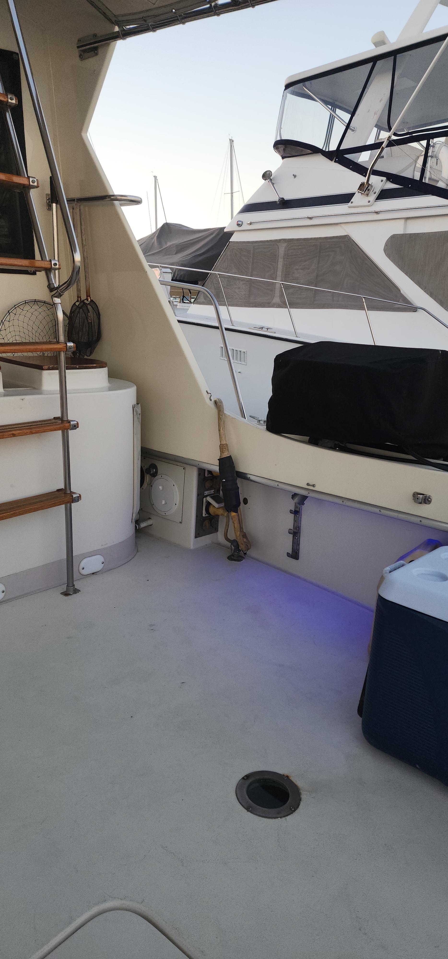 1978 Hatteras Sportfish boat deck with visible stairs and adjacent docked vessel.