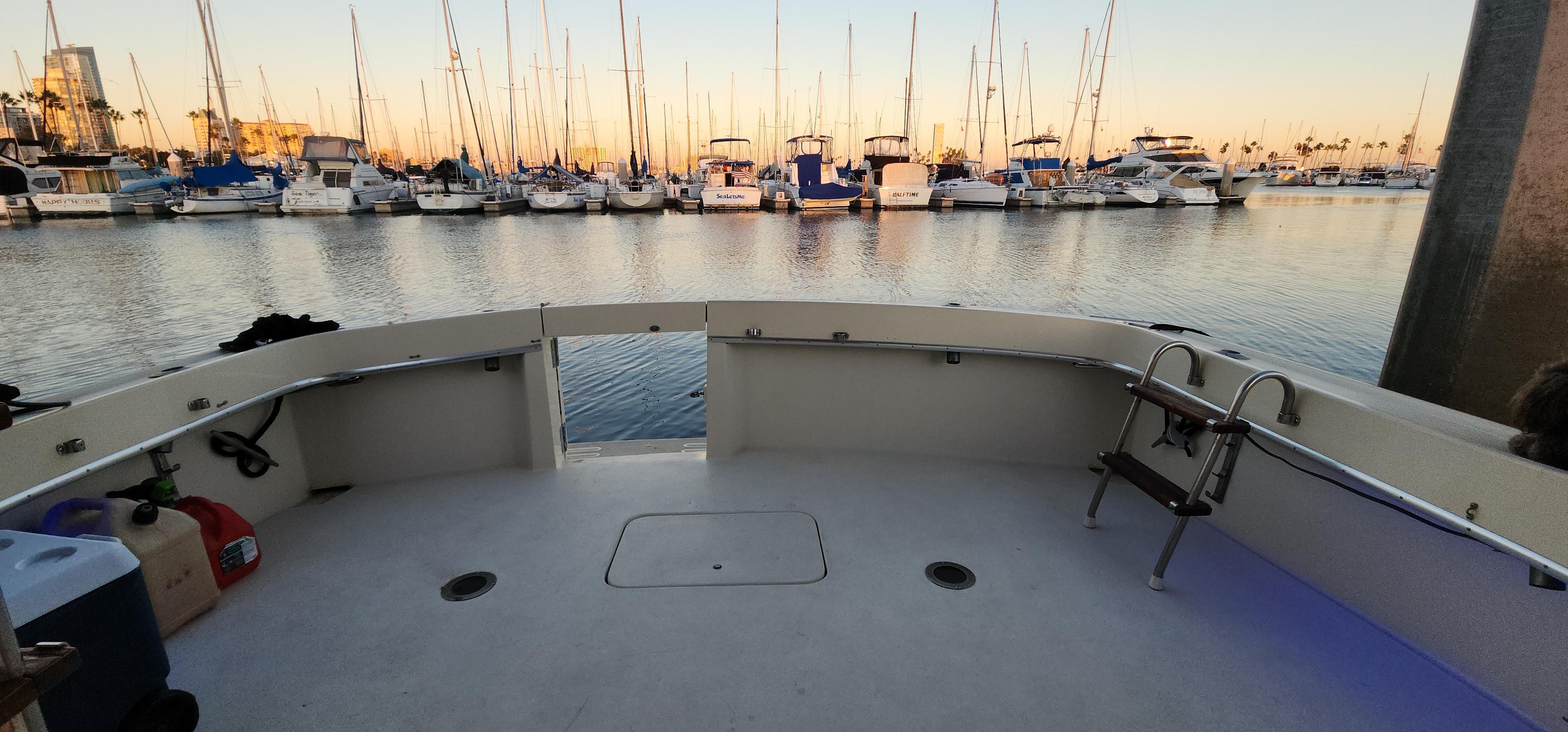 1978 Hatteras Sportfish boat docked at marina with sailboats in background.