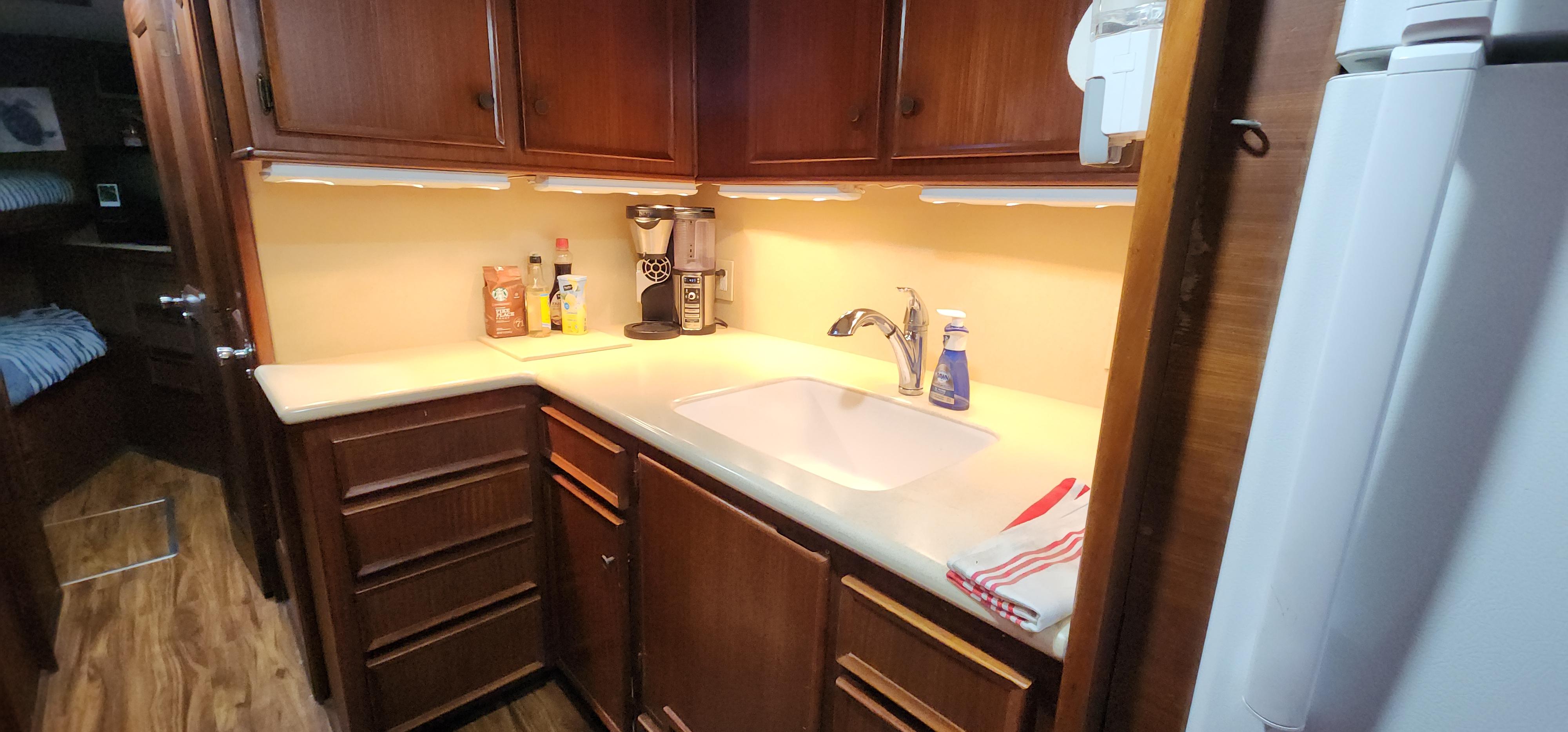 1978 Hatteras Sportfish kitchen with wooden cabinets, sink, and countertop appliances.