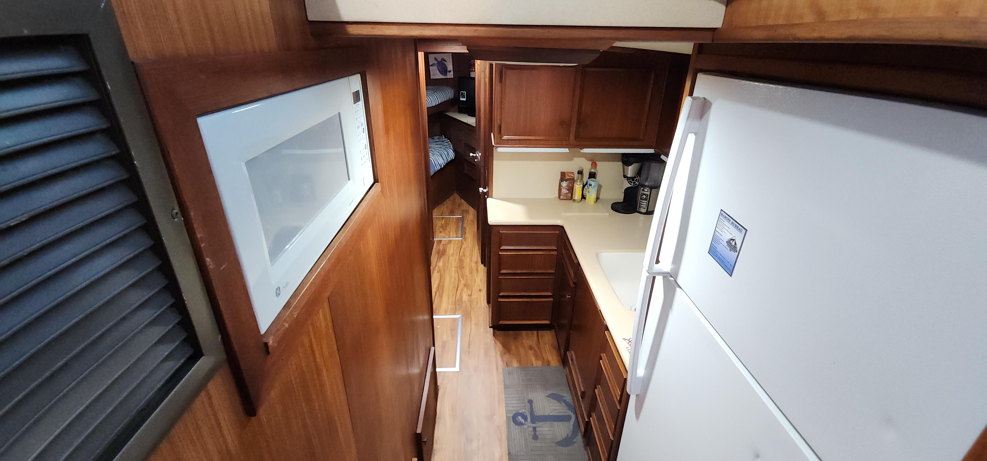 1978 Hatteras Sportfish interior kitchen with wooden cabinets and white appliances.