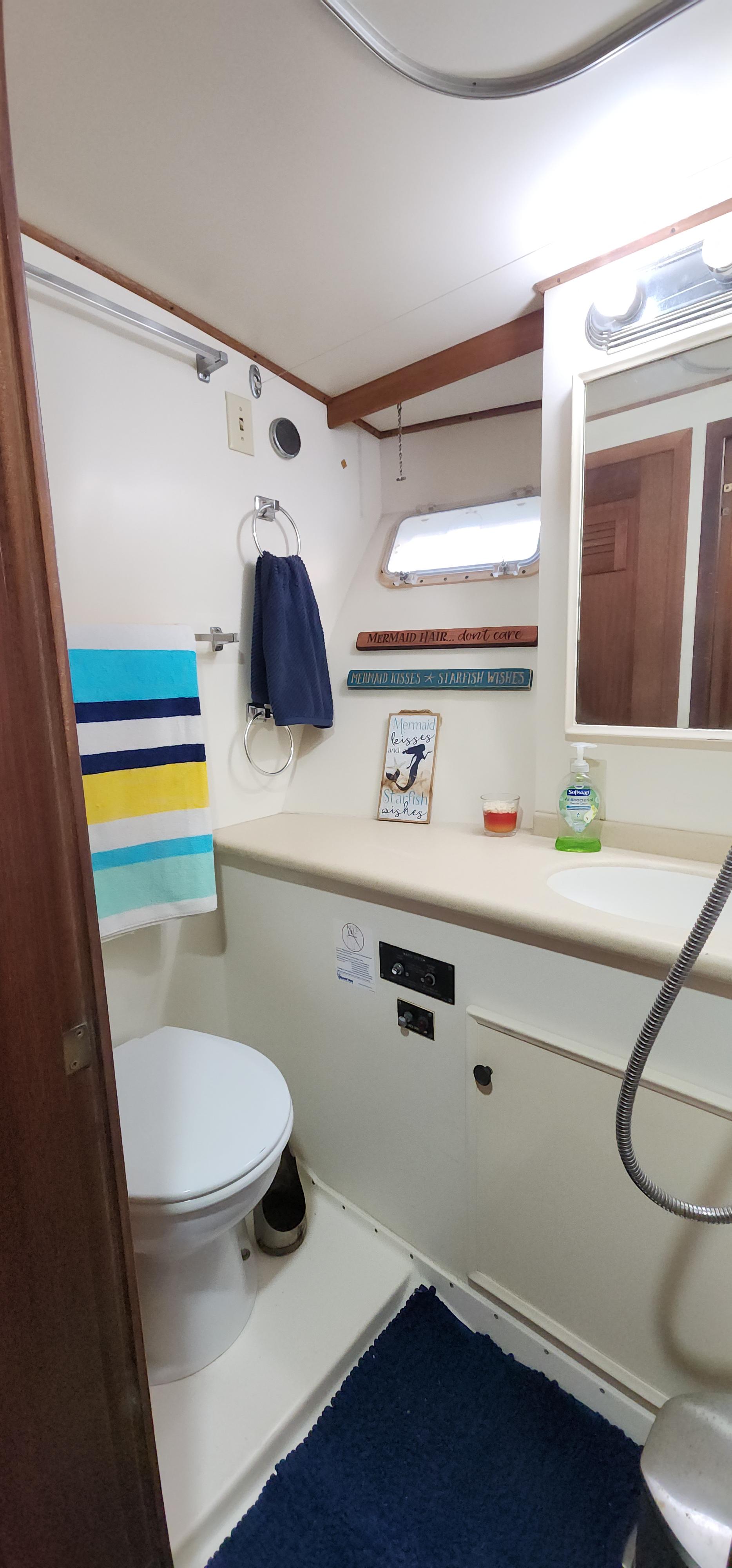 1978 Hatteras Sportfish bathroom with toilet, sink, mirror, and colorful towels.