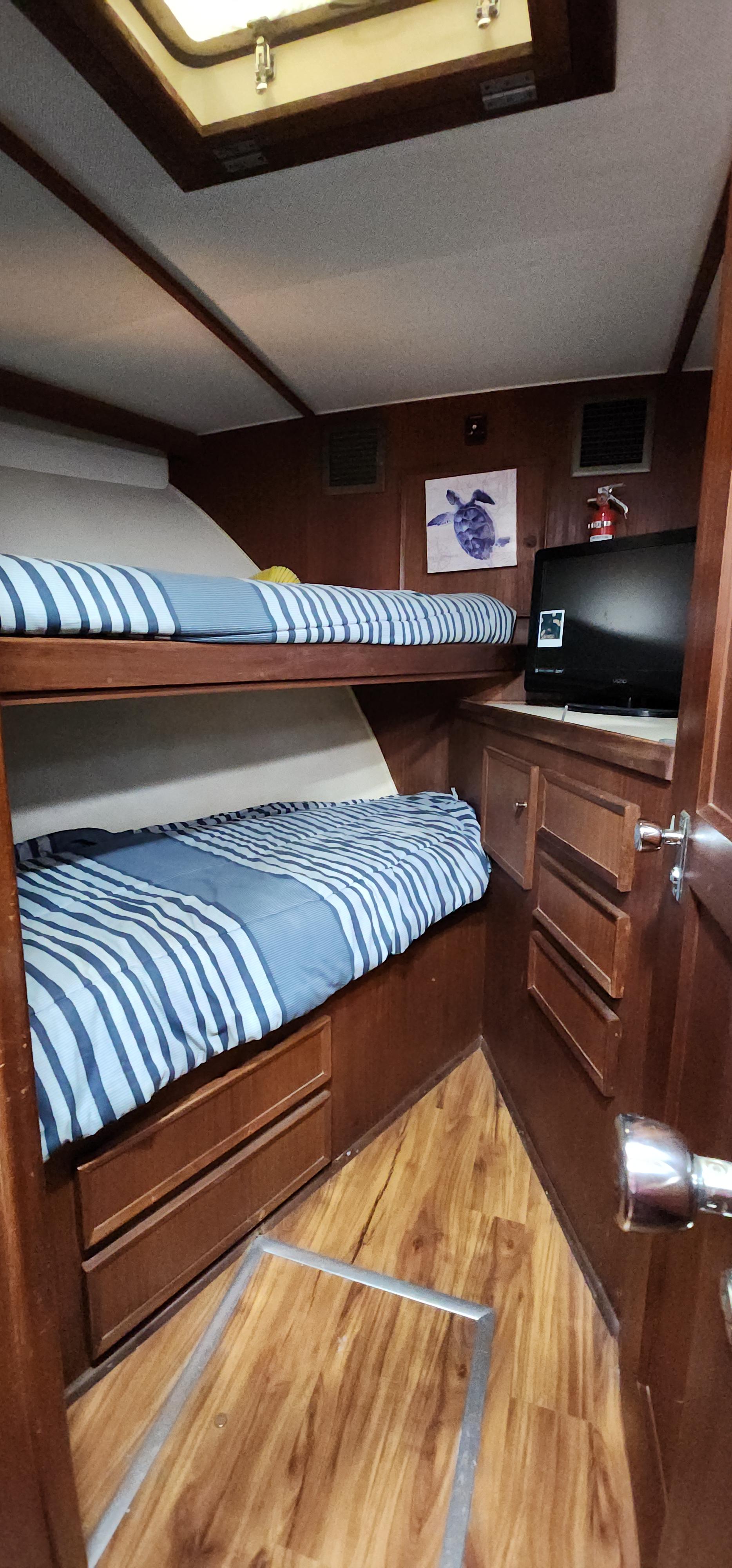 1978 Hatteras Sportfish cabin with bunk beds, wood paneling, and striped bedding.