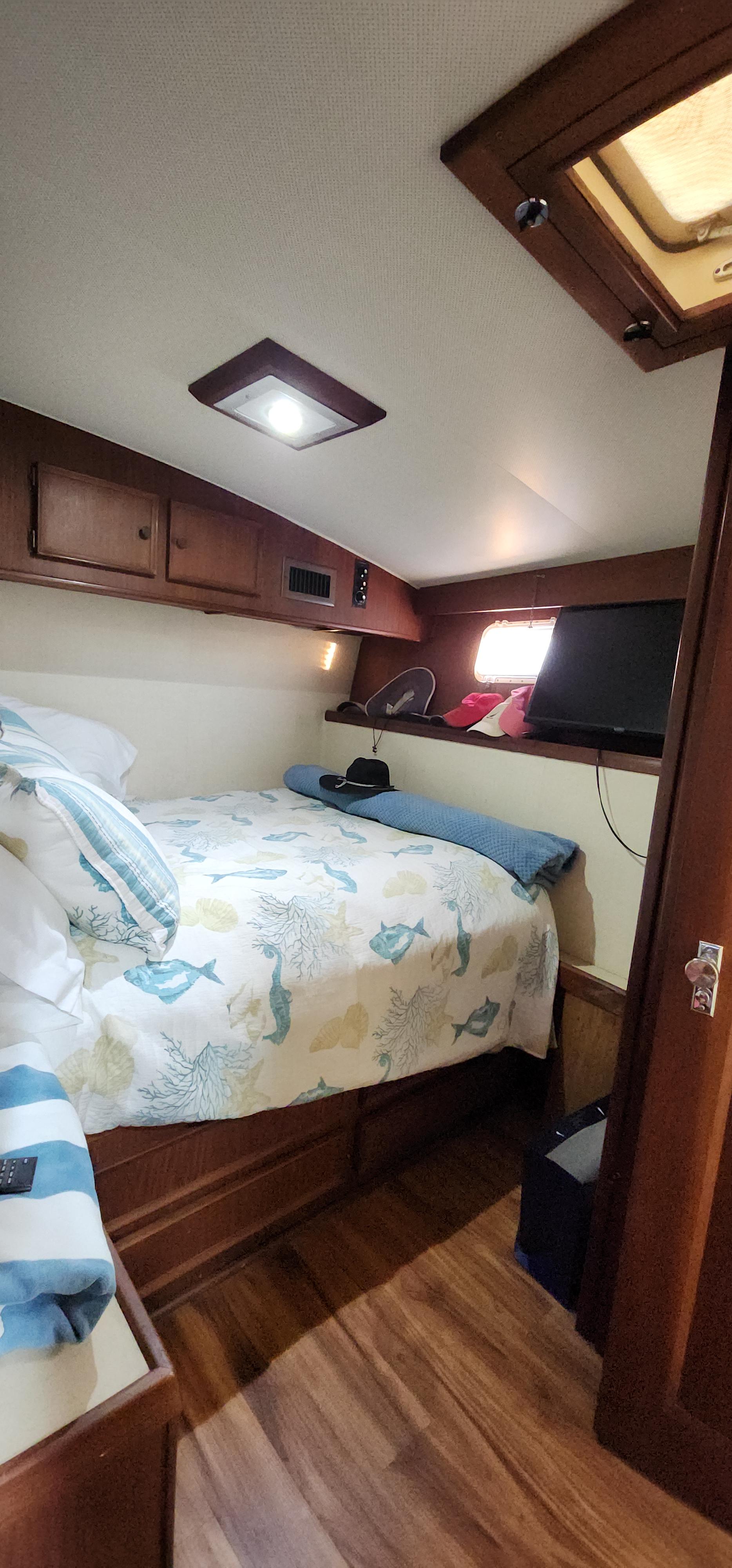 1978 Hatteras Sportfish cabin interior with bed, wooden cabinets, and TV.