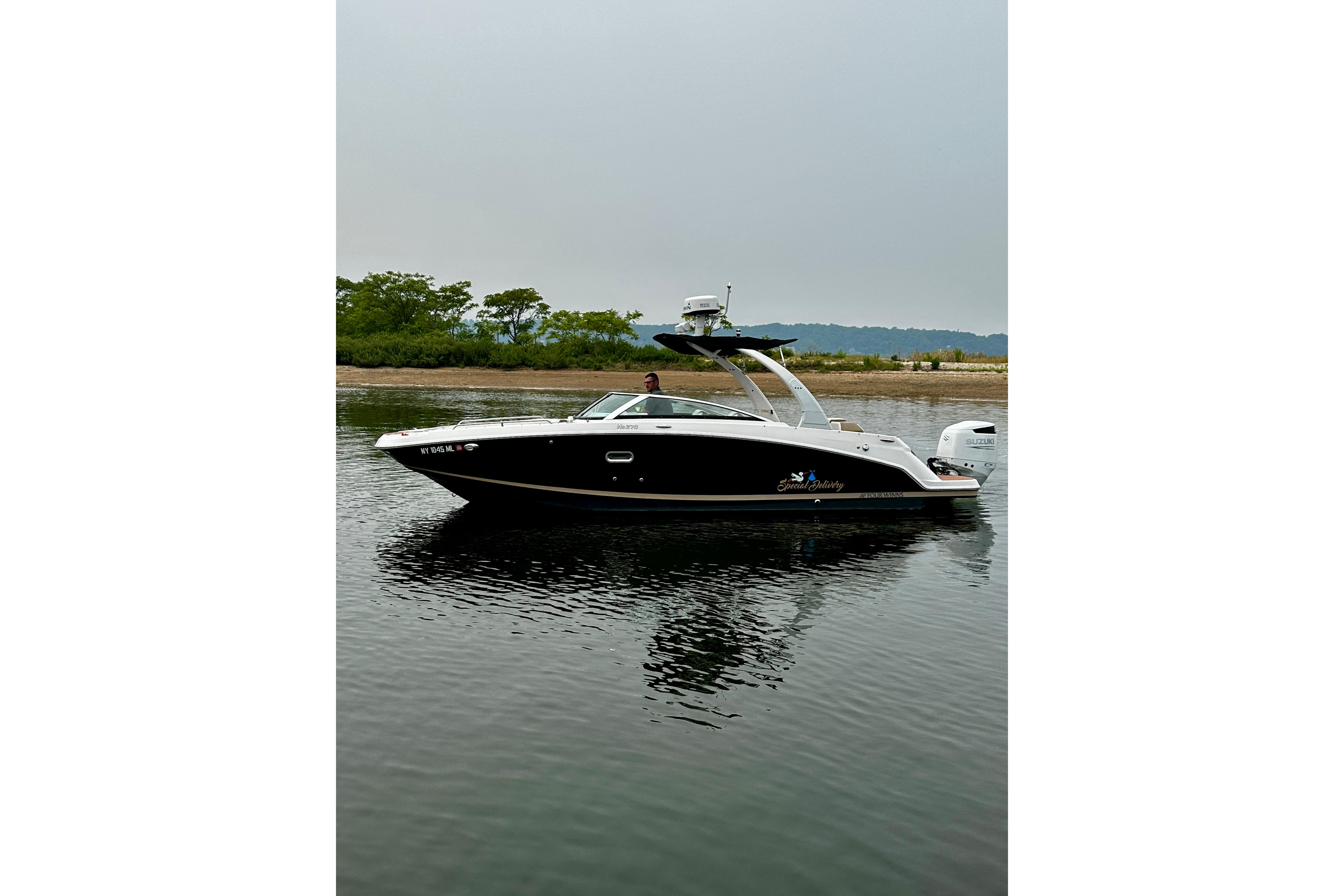 2016 Four Winns Ho270 boat on calm water, with lush greenery in the background.