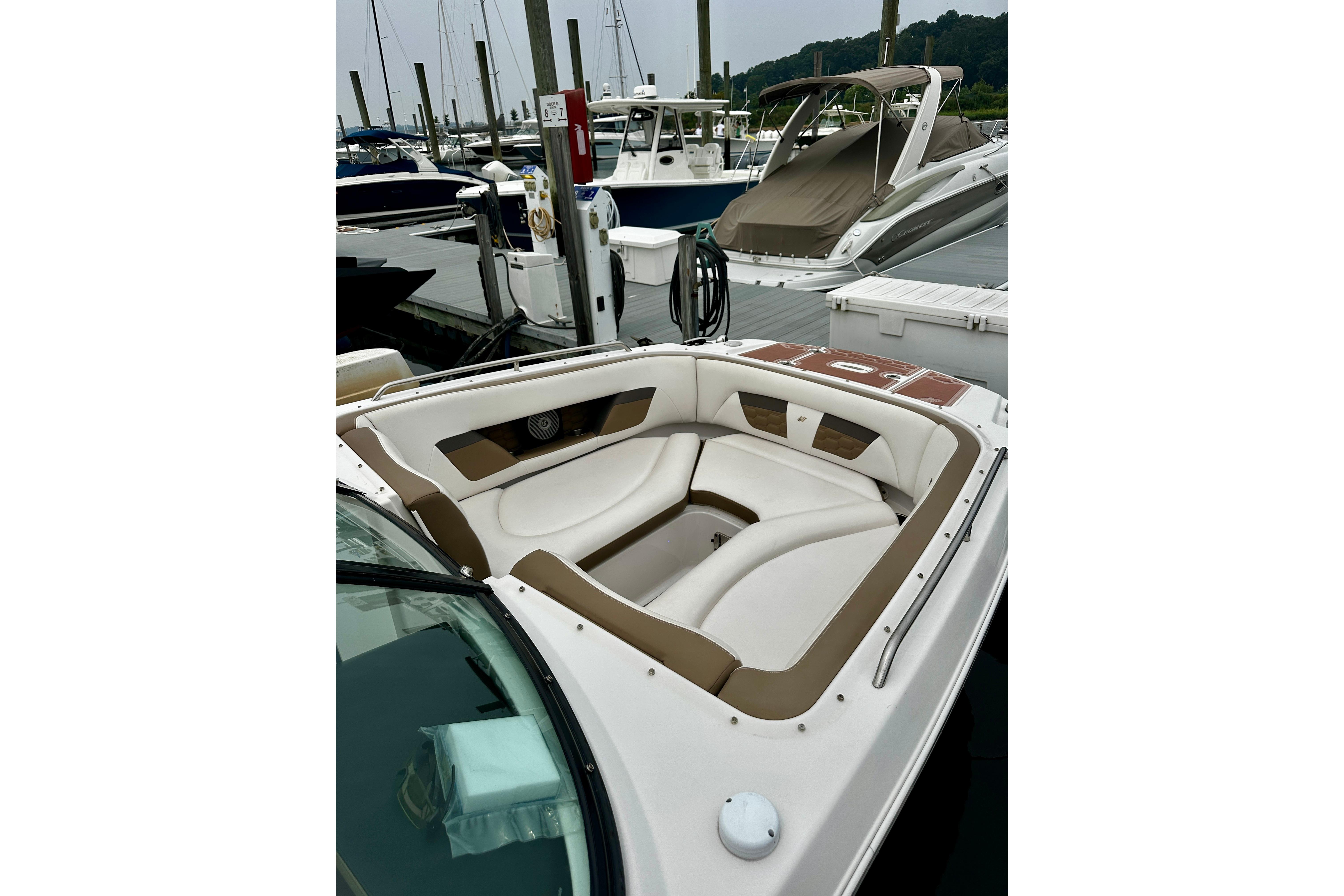 2016 Four Winns Ho270 boat with white and brown seating at a marina dock.