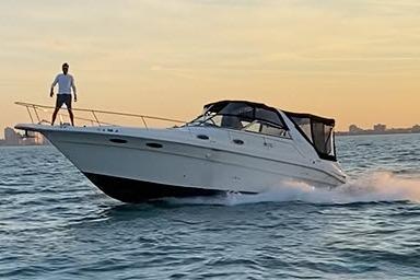 1996 Sea Ray 330 Sundancer cruising at sunset with a person on deck.