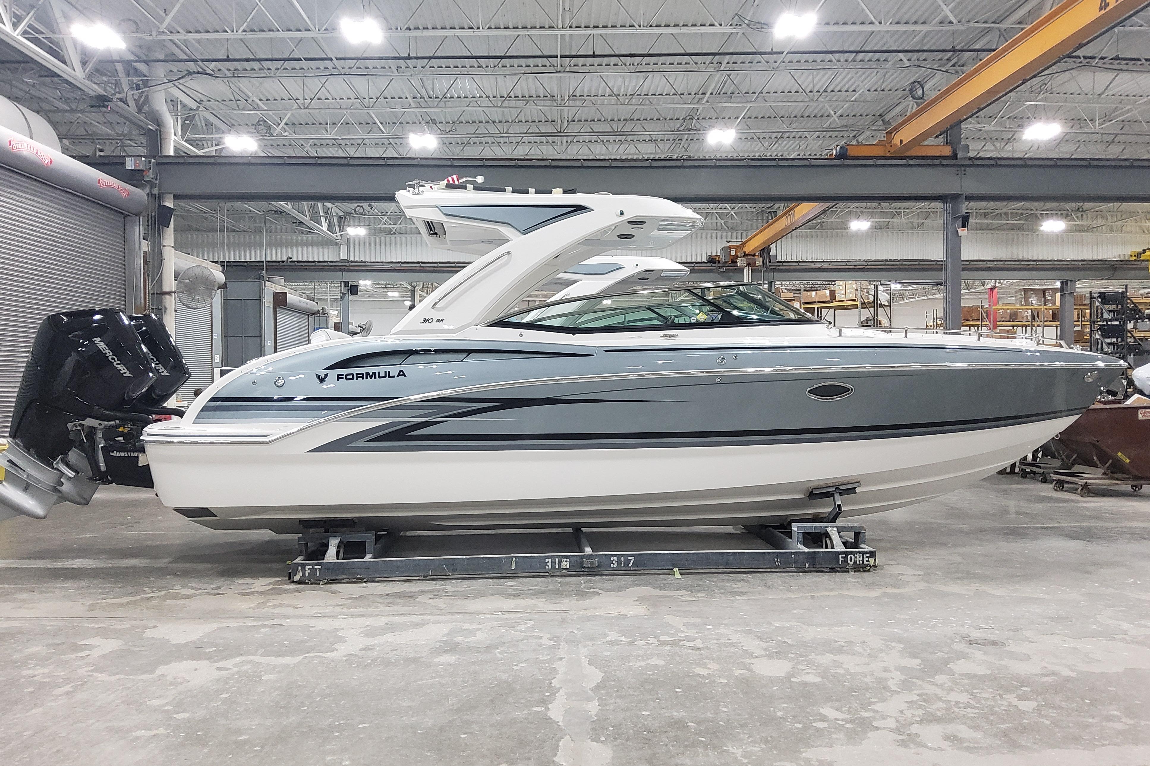 2026 Formula 310 Bowrider OB in a warehouse, showcasing sleek design and powerful outboard engines.