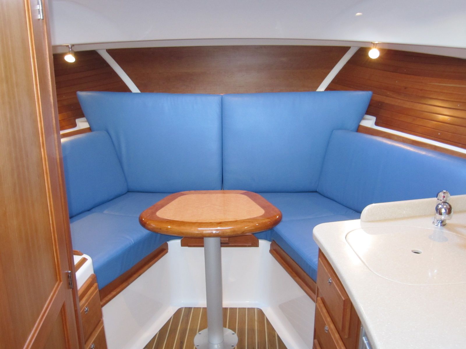 Interior of 2011 Back Cove 30 boat with blue seating and wooden table.