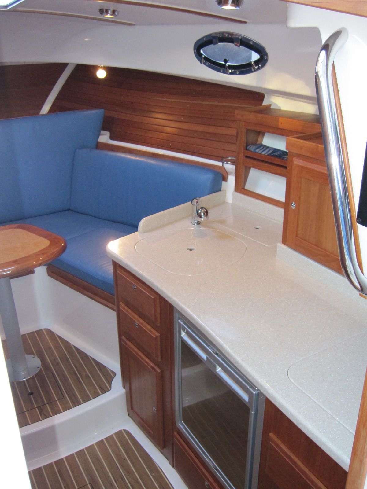 2011 Back Cove 30 yacht interior with kitchenette, blue seating, and wooden cabinetry.