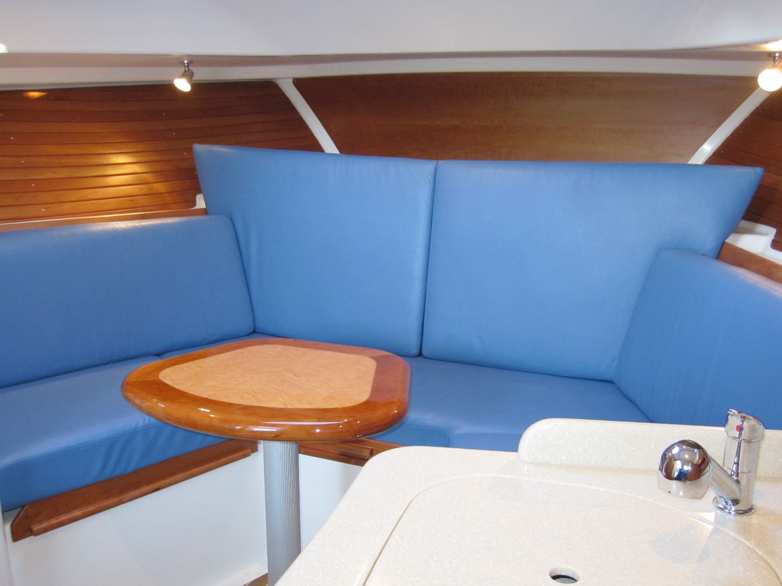 Interior of 2011 Back Cove 30 boat with blue seating and wooden table.
