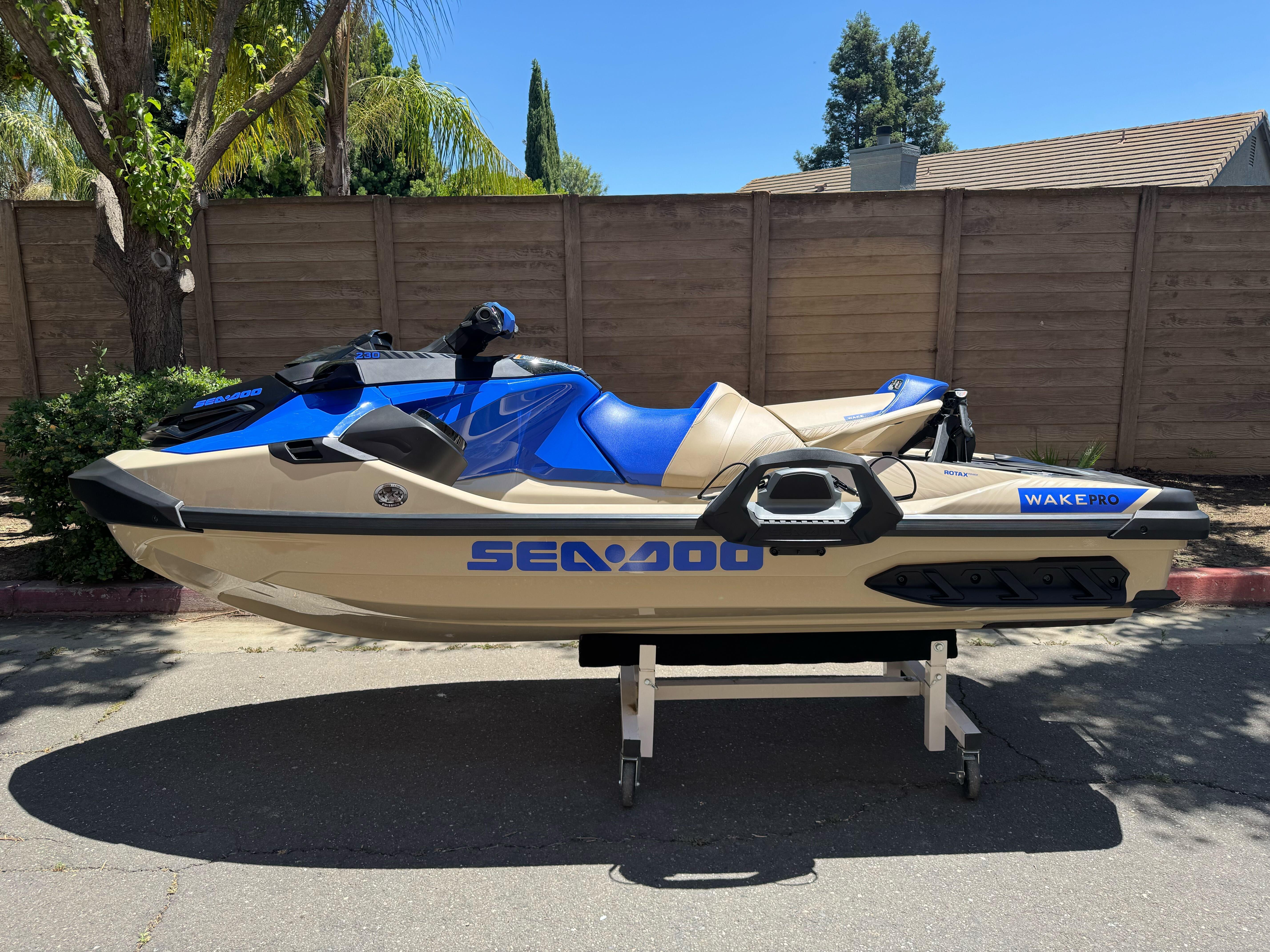 2025 Sea-Doo Wake Pro 230 jet ski, blue and beige, parked outdoors.