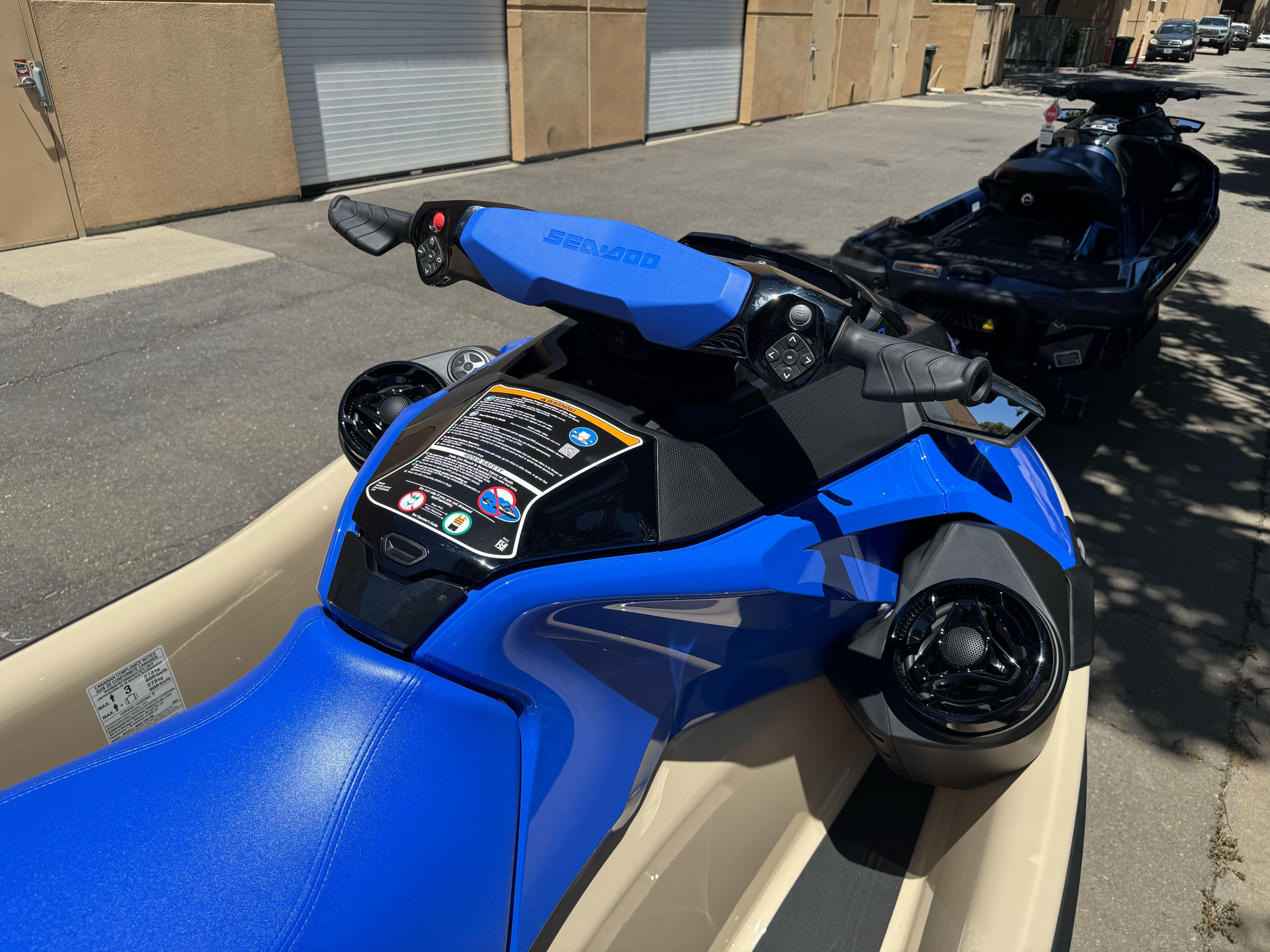 2025 Sea-Doo Wake Pro 230 jet ski, blue, parked outdoors, close-up of handlebars and seat.