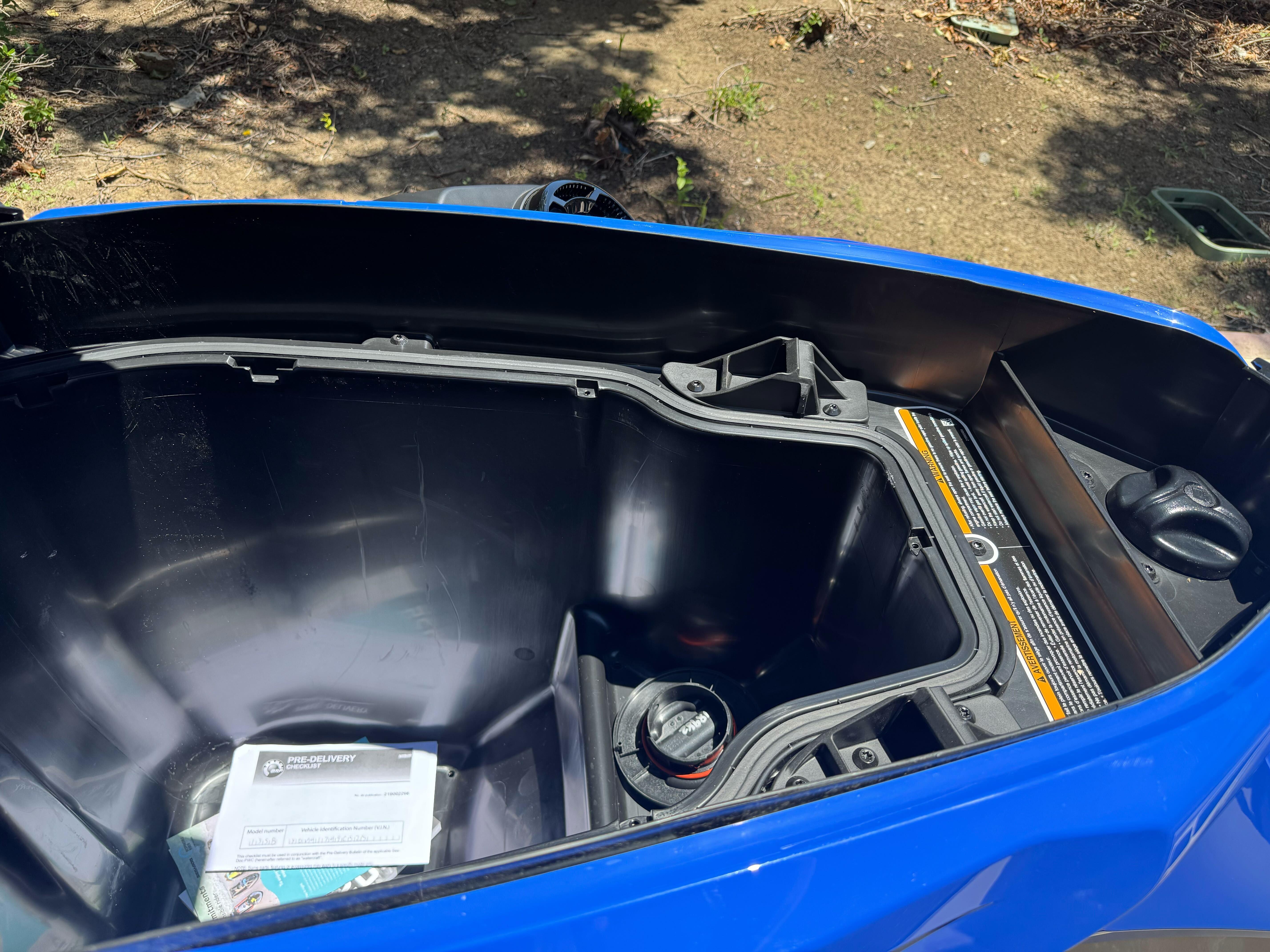 Open storage compartment of 2025 Sea-Doo Wake Pro 230, showing interior details and manual.