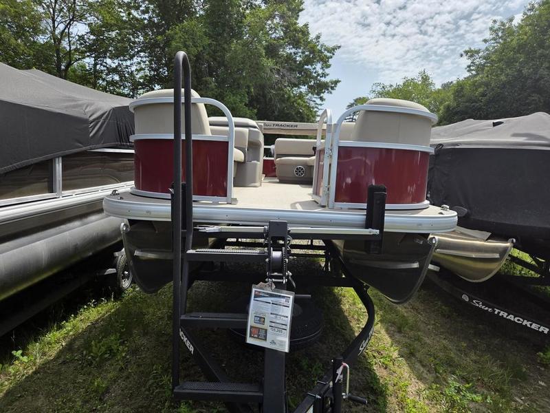 2025 Sun Tracker PB 18 DLX pontoon boat on trailer, surrounded by trees.