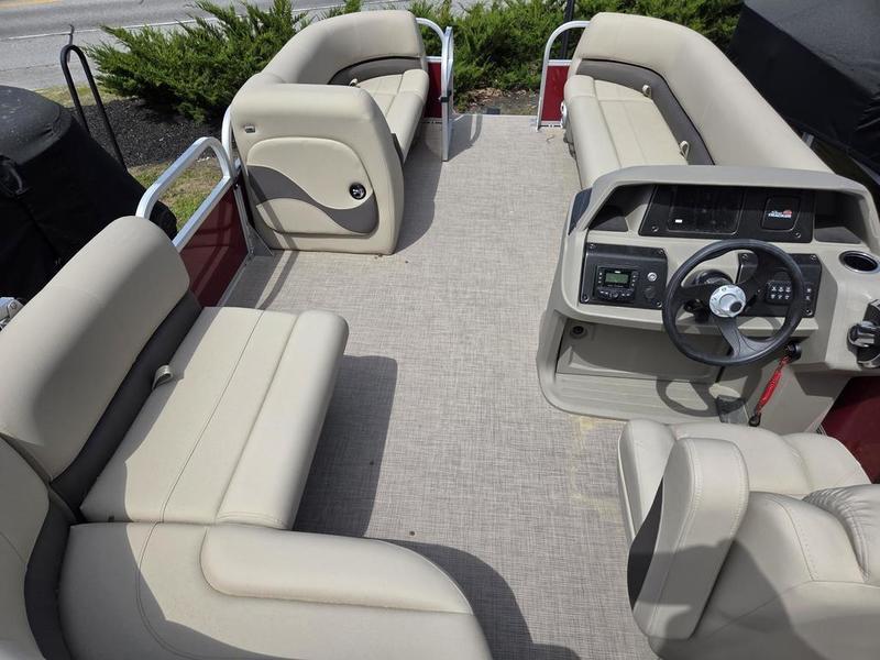 2025 Sun Tracker PB 18 DLX pontoon boat interior with beige seating and steering console.