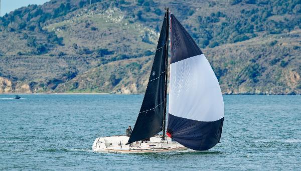 2005 J Boats J/100 sailing on a scenic lake with hills in the background.
