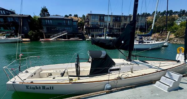 2005 J Boats J/100 sailboat docked in a marina with waterfront homes.