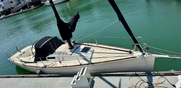 2005 J Boats J/100 sailboat docked in a marina, featuring sleek design and covered sails.