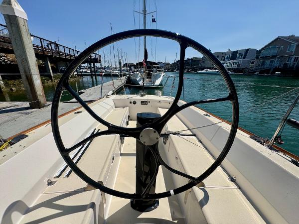 2005 J Boats J/100 sailboat cockpit with steering wheel, docked in a marina.