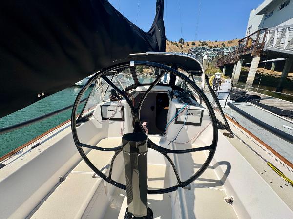 2005 J Boats J/100 sailboat cockpit with steering wheel, docked by waterfront homes.