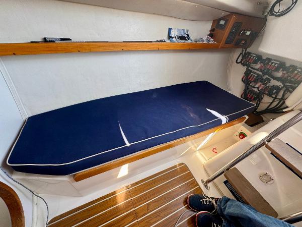 Interior of 2005 J Boats J/100 sailboat with blue cushioned bench and wooden accents.