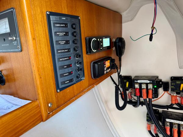 Control panel inside a 2005 J Boats J/100 sailboat, featuring switches and communication equipment.