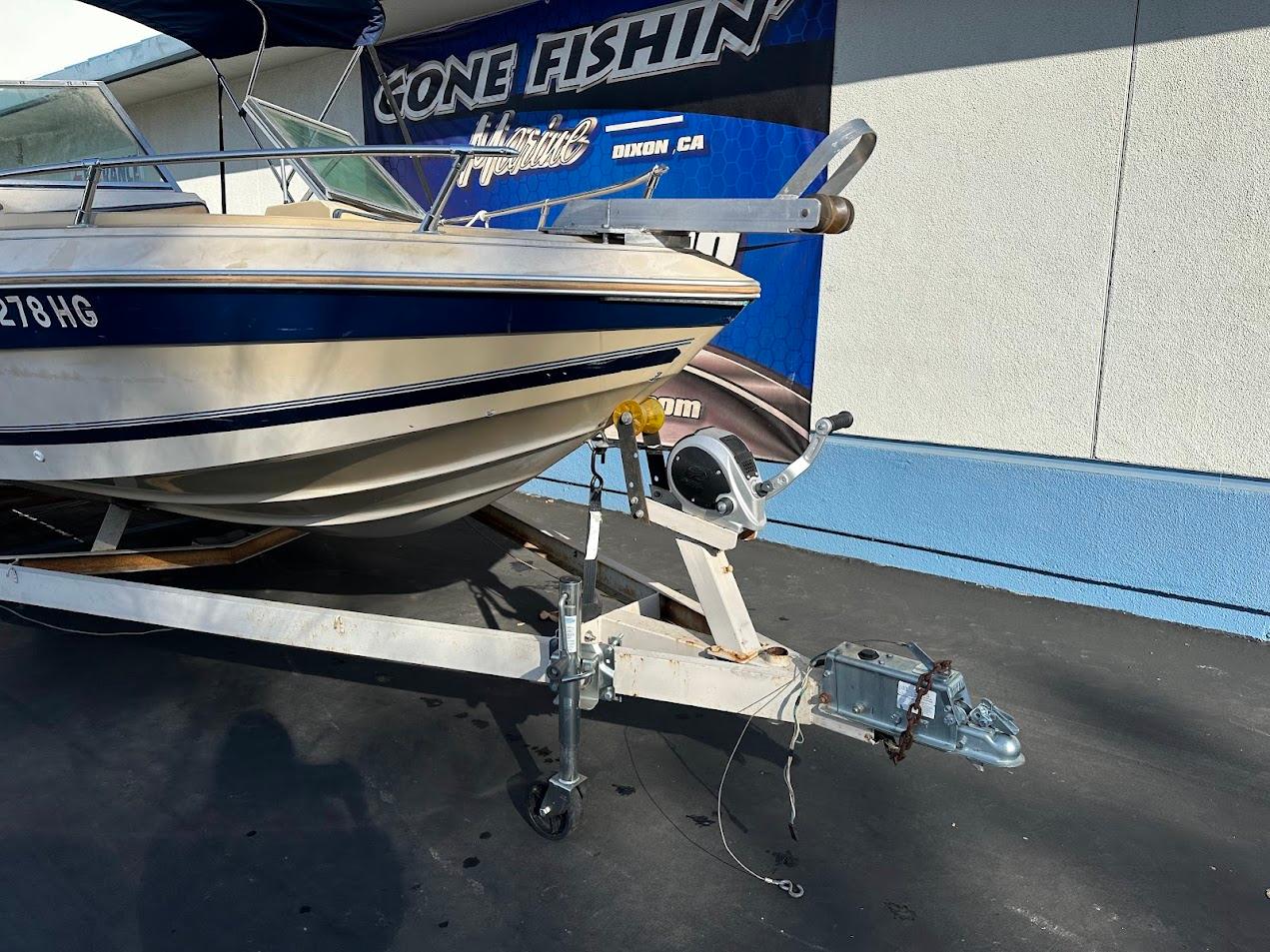 1987 Seaswirl Sierra II boat on trailer, parked outside a fishing store.