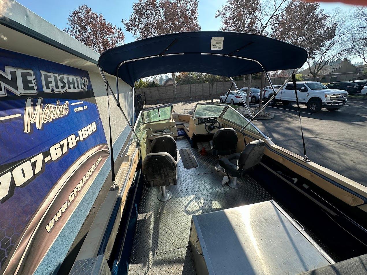 1987 Seaswirl Sierra II boat with canopy, parked outdoors, featuring dual seating and steering wheel.