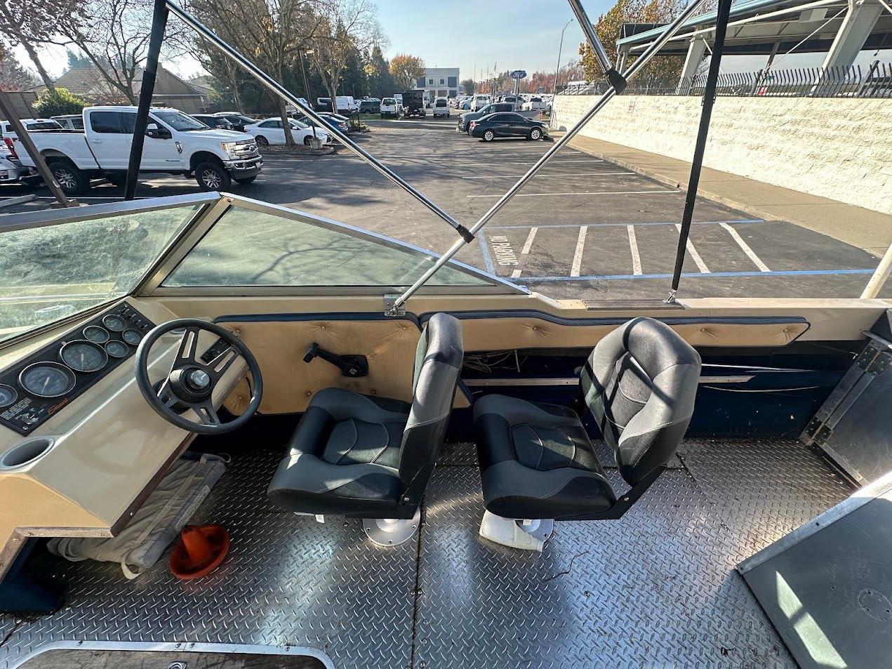 1987 Seaswirl Sierra II boat interior with steering wheel and two seats in a parking lot.
