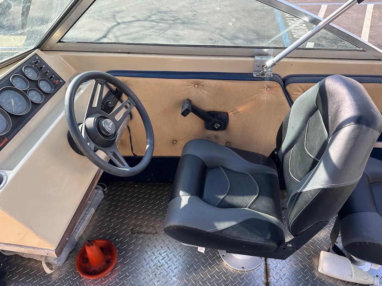 Interior of 1987 Seaswirl Sierra II boat with steering wheel and black seat.