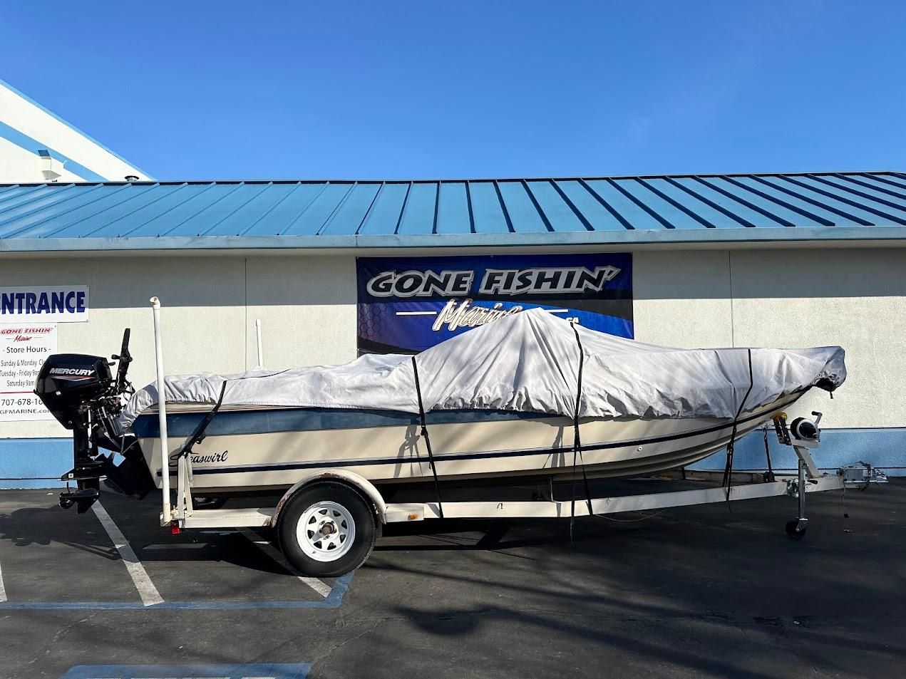 1987 Seaswirl Sierra II boat covered on trailer, parked outside a building.