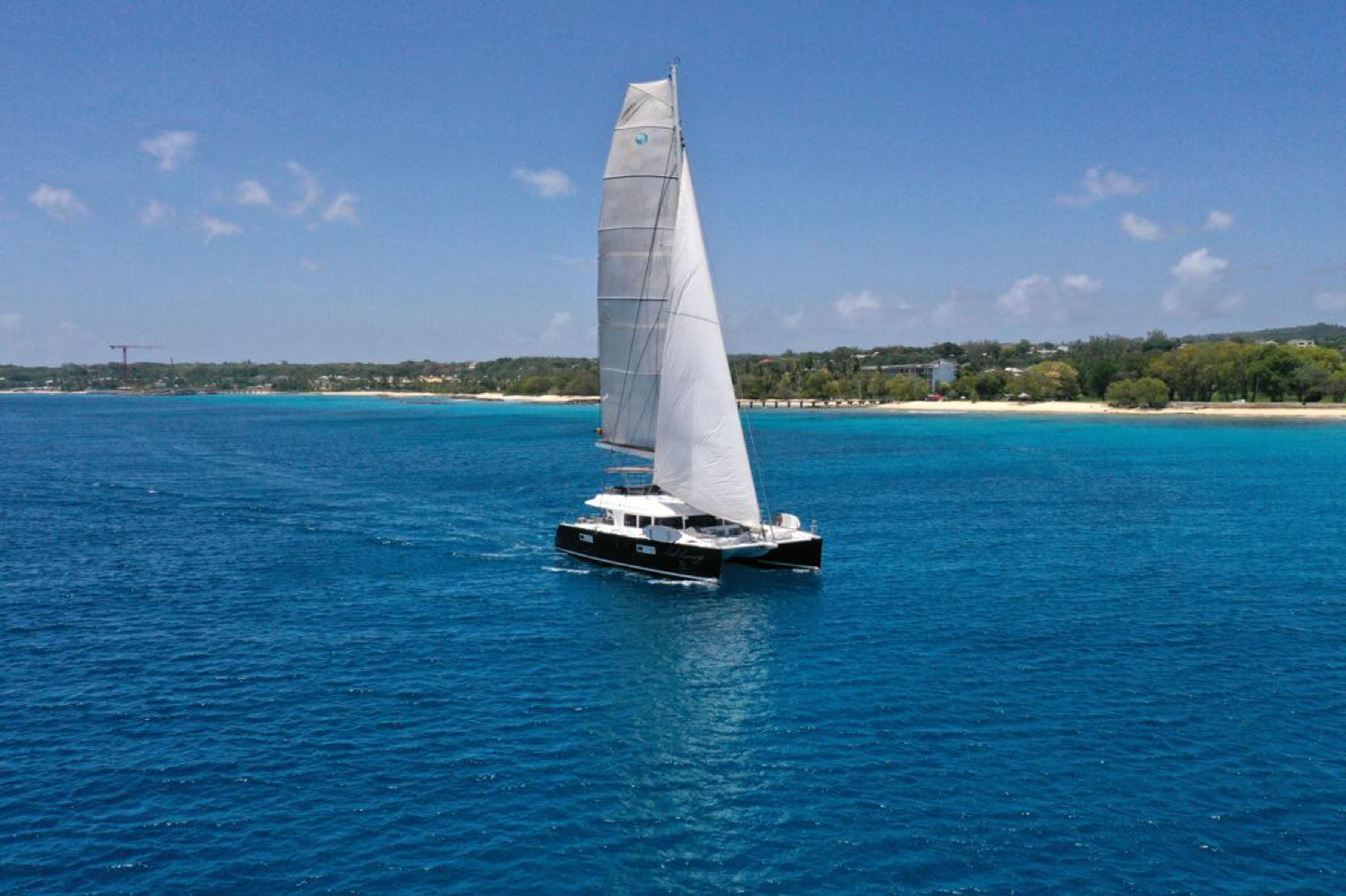 Lagoon-560 S2 2015-Cool Runnings IV SC-US-Lagoon 560 S2 catamaran sailing on clear blue waters near a sandy coastline, 2015 model.-9782915