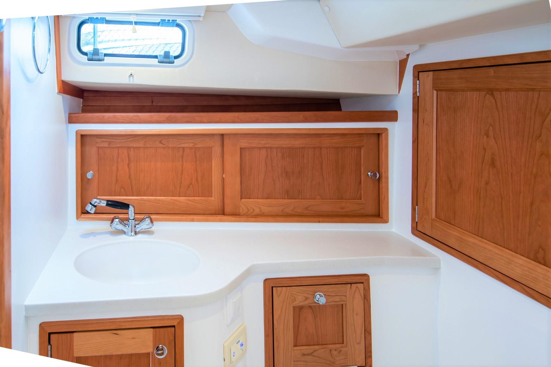 2023 MJM 35 yacht interior with wooden cabinets and sink in compact bathroom.