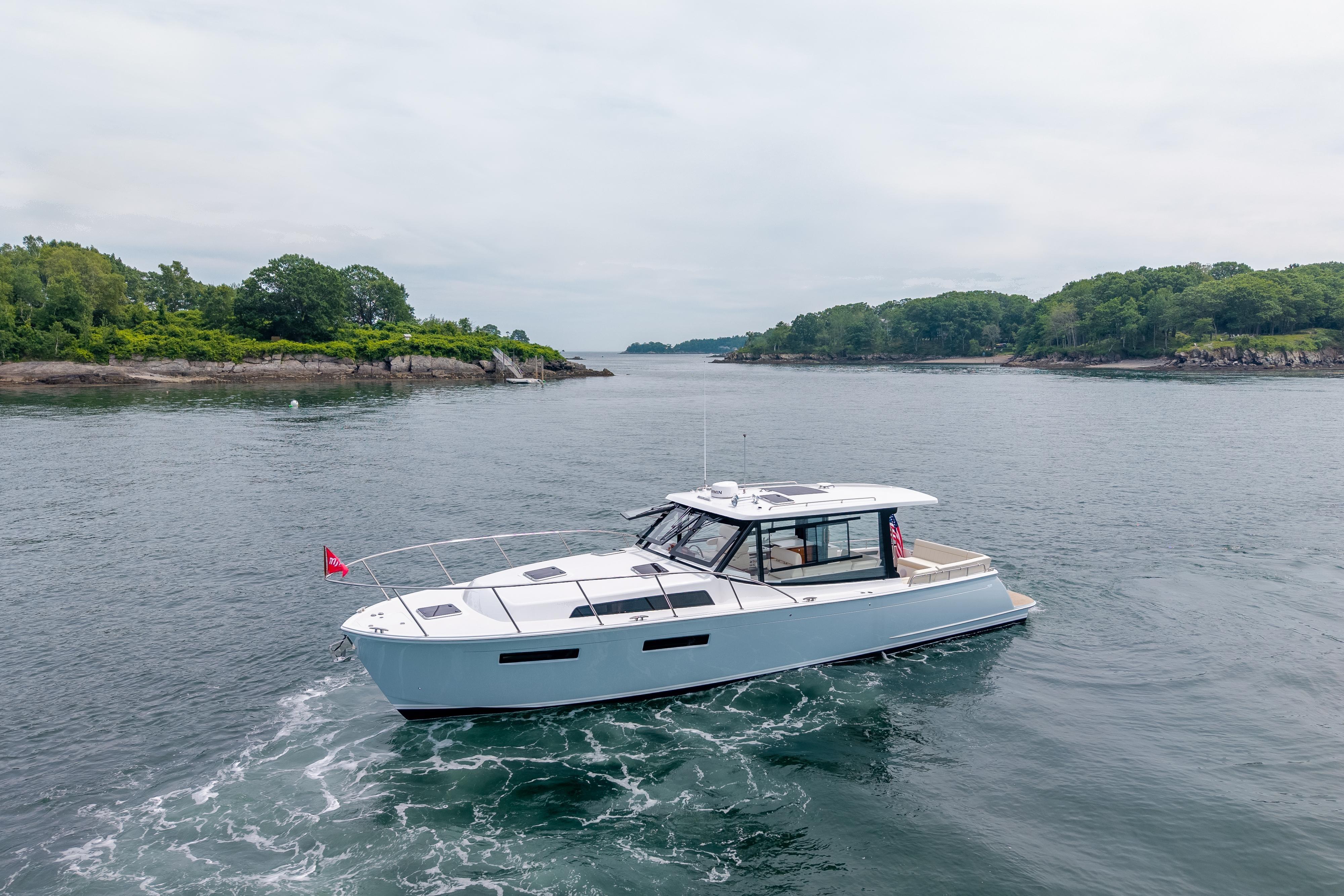 2025 MJM 42 yacht cruising near lush, green shoreline.