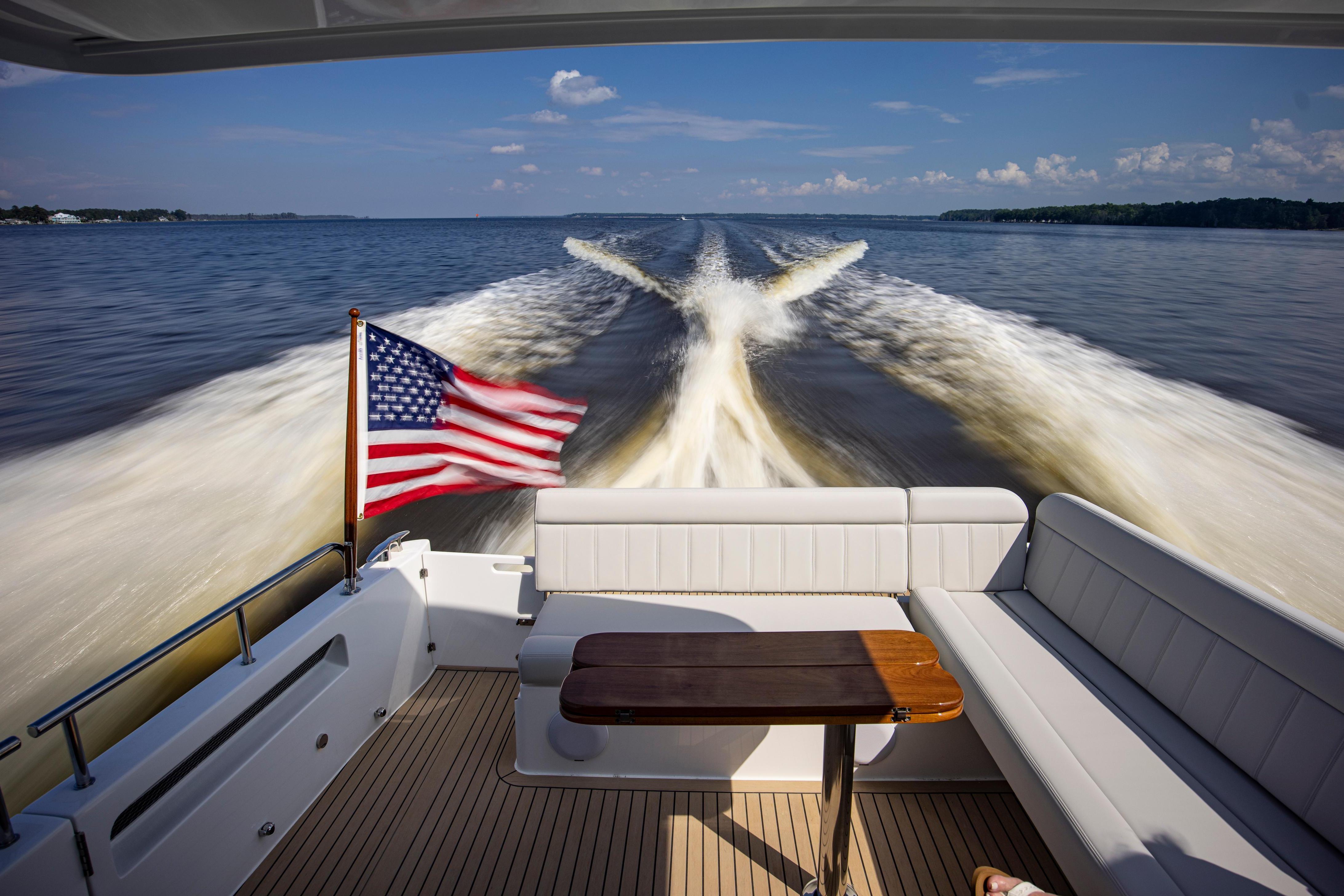 A 2025 MJM 42 yacht cruising with American flag, leaving a wake on the water.