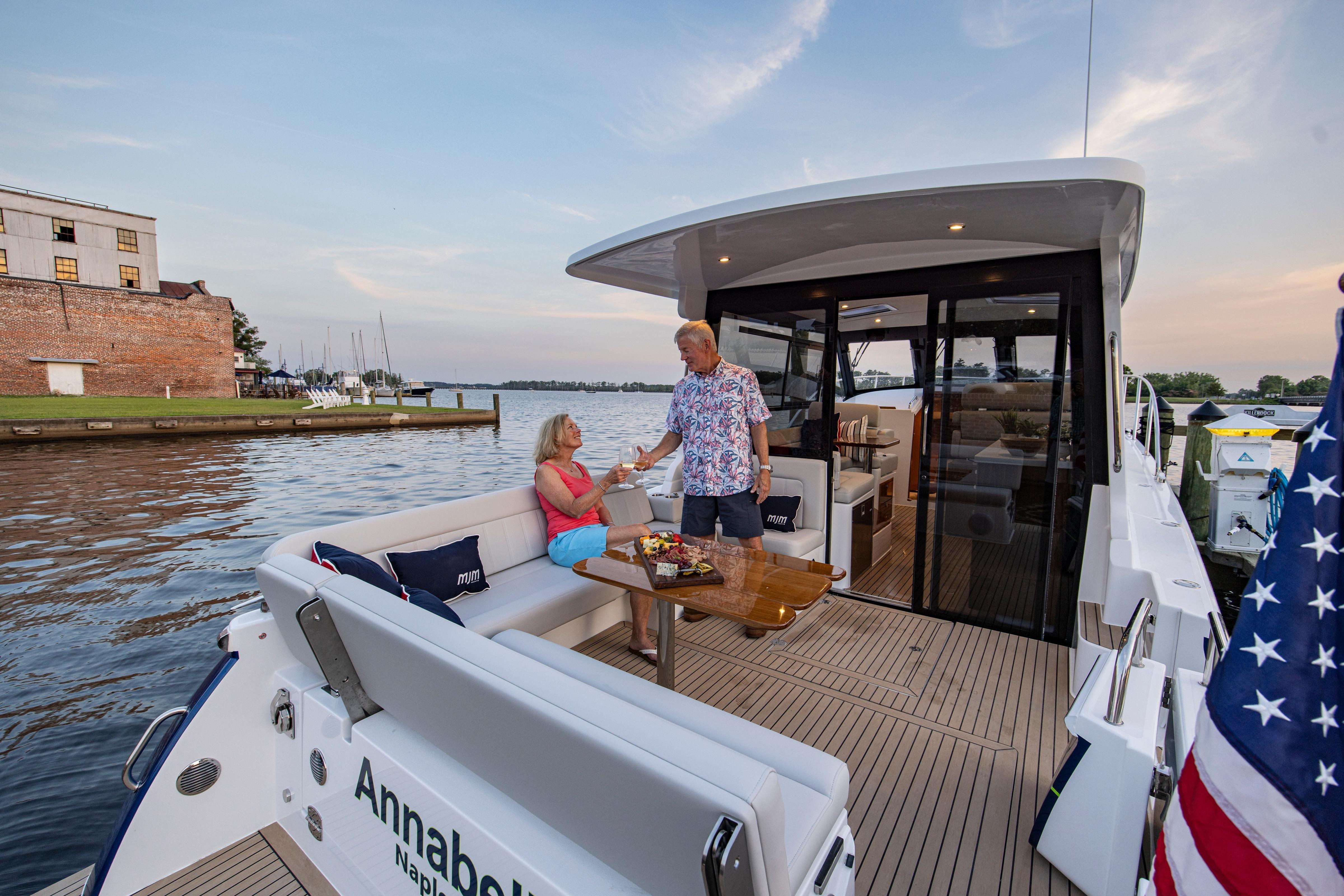 Couple enjoying leisure time on 2025 MJM 42 yacht, docked by scenic waterfront.