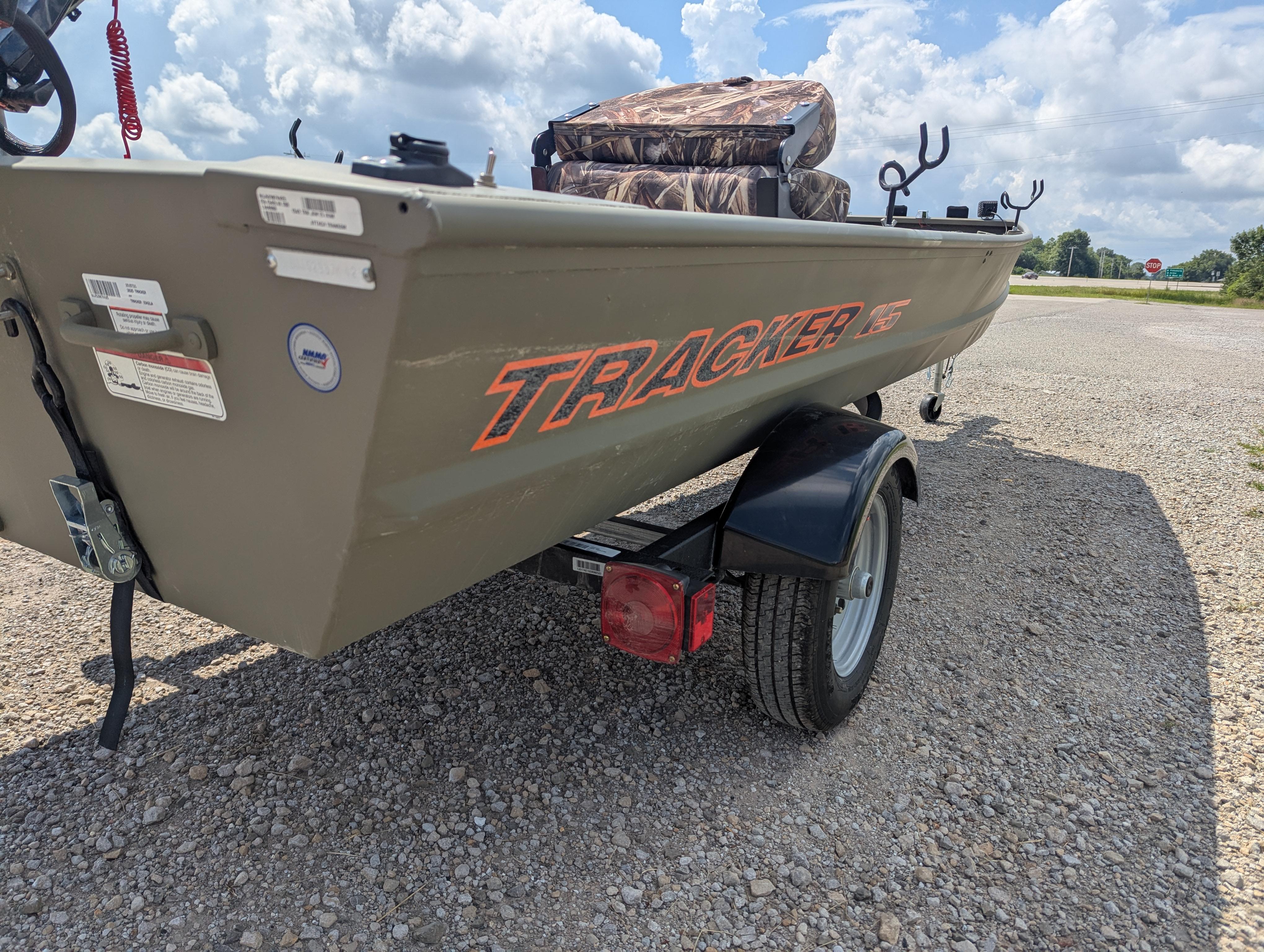 2025 Tracker Grizzly 15 Jon boat on trailer, parked on gravel under cloudy sky.