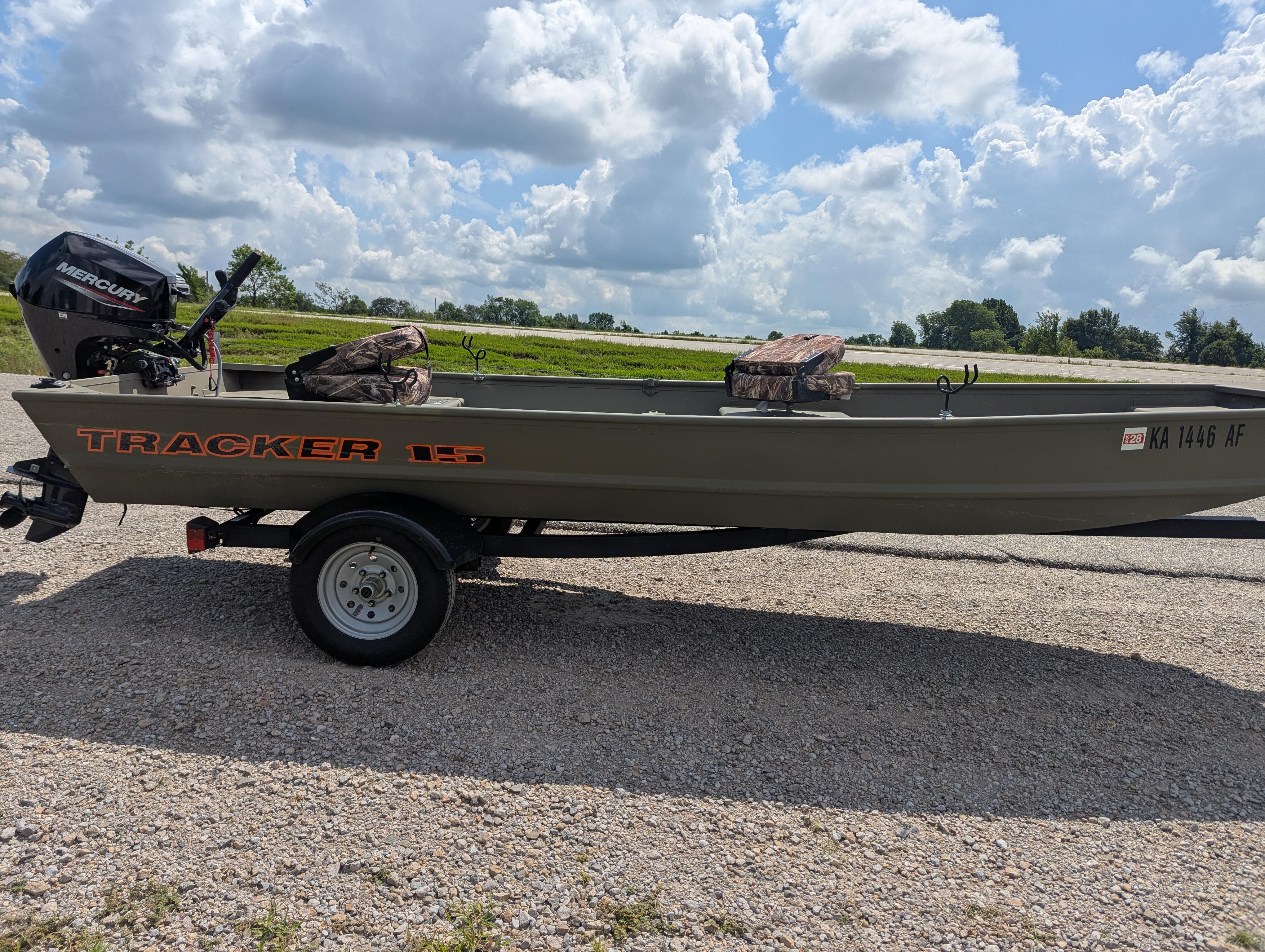 2025 Tracker Grizzly 15 Jon boat on trailer, parked on gravel road under cloudy sky.