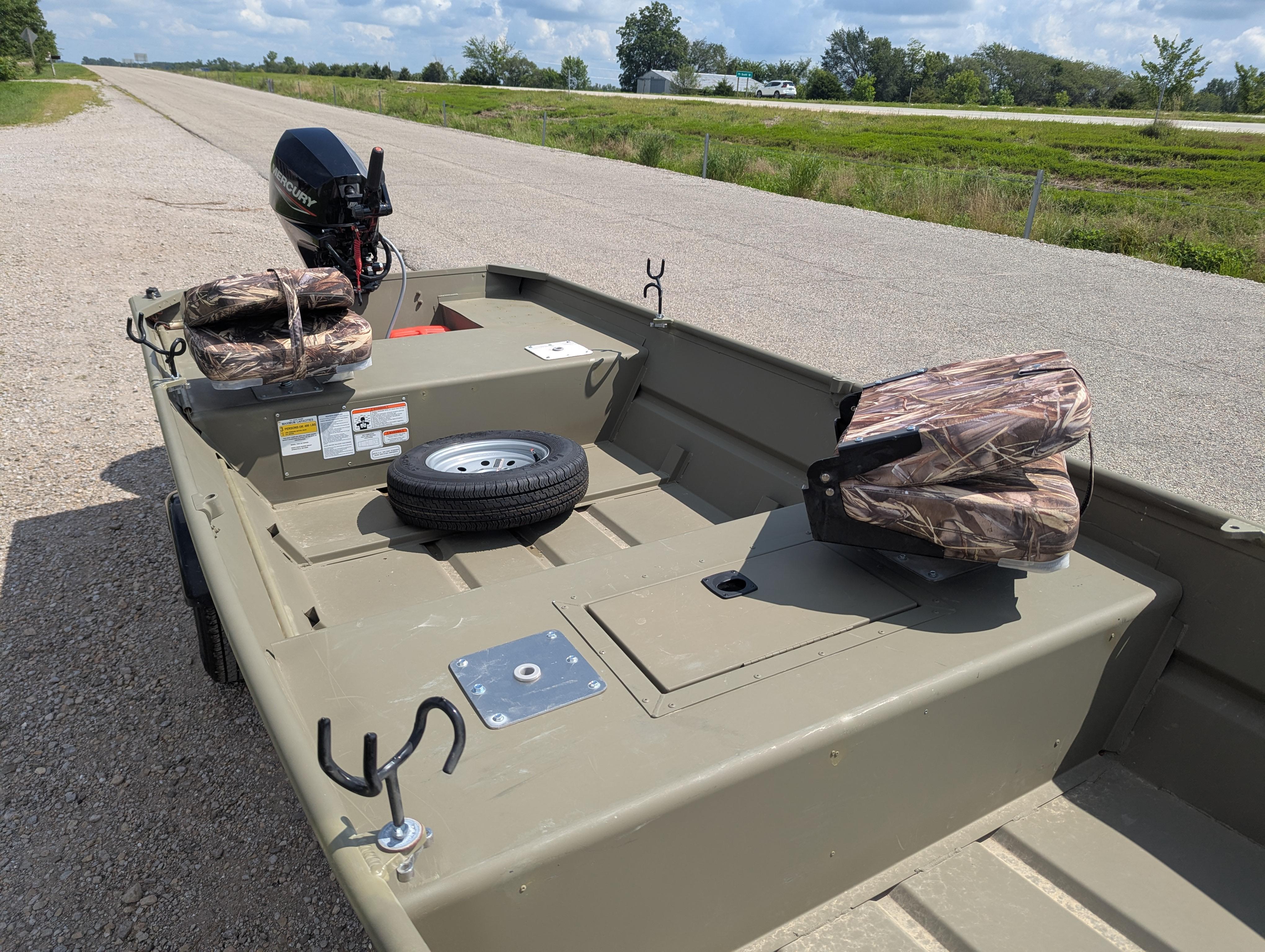 2025 Tracker Grizzly 15 Jon boat with motor, camo seats, and spare tire on roadside.