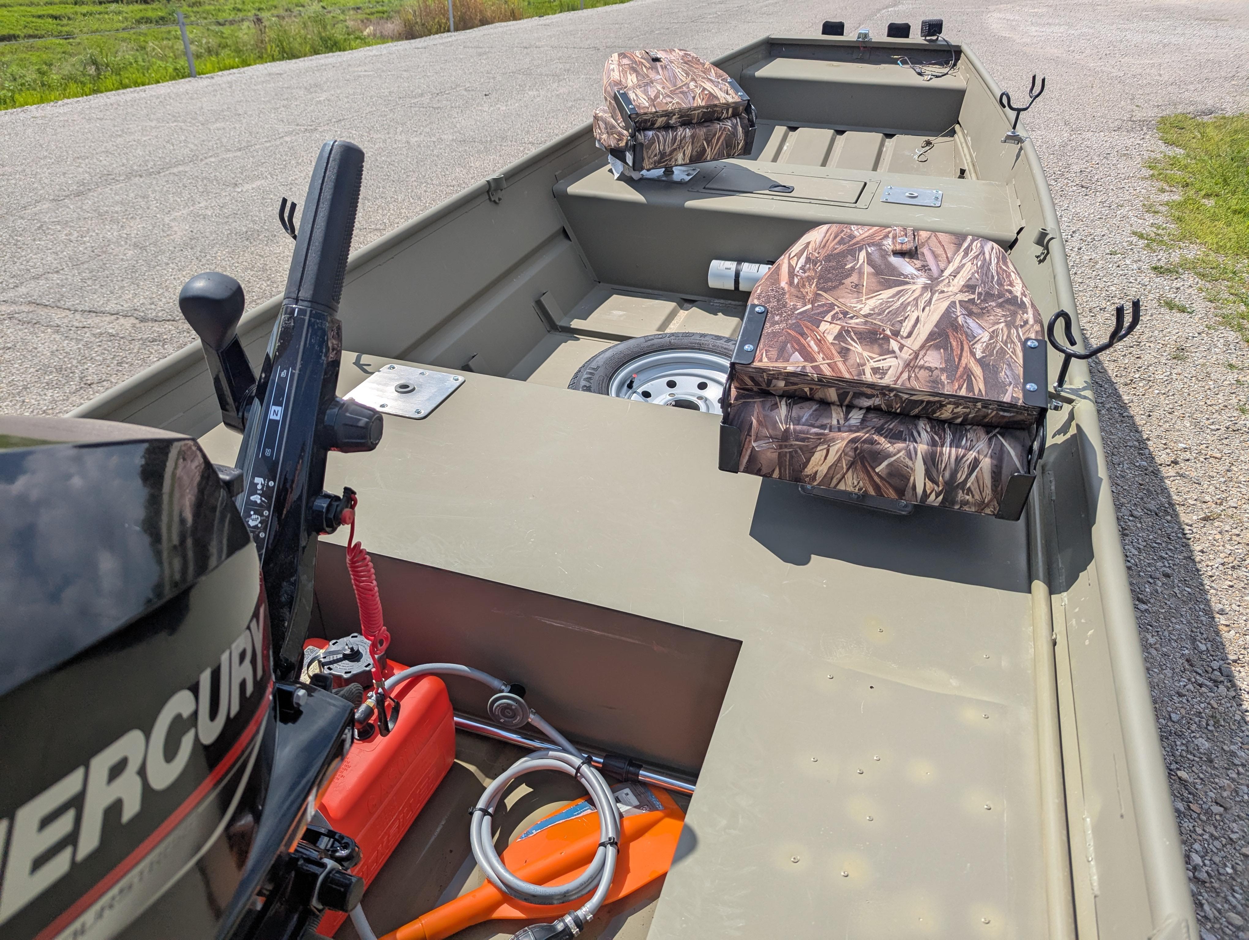 2025 Tracker Grizzly 15 Jon boat with camo seats and Mercury motor on a gravel path.