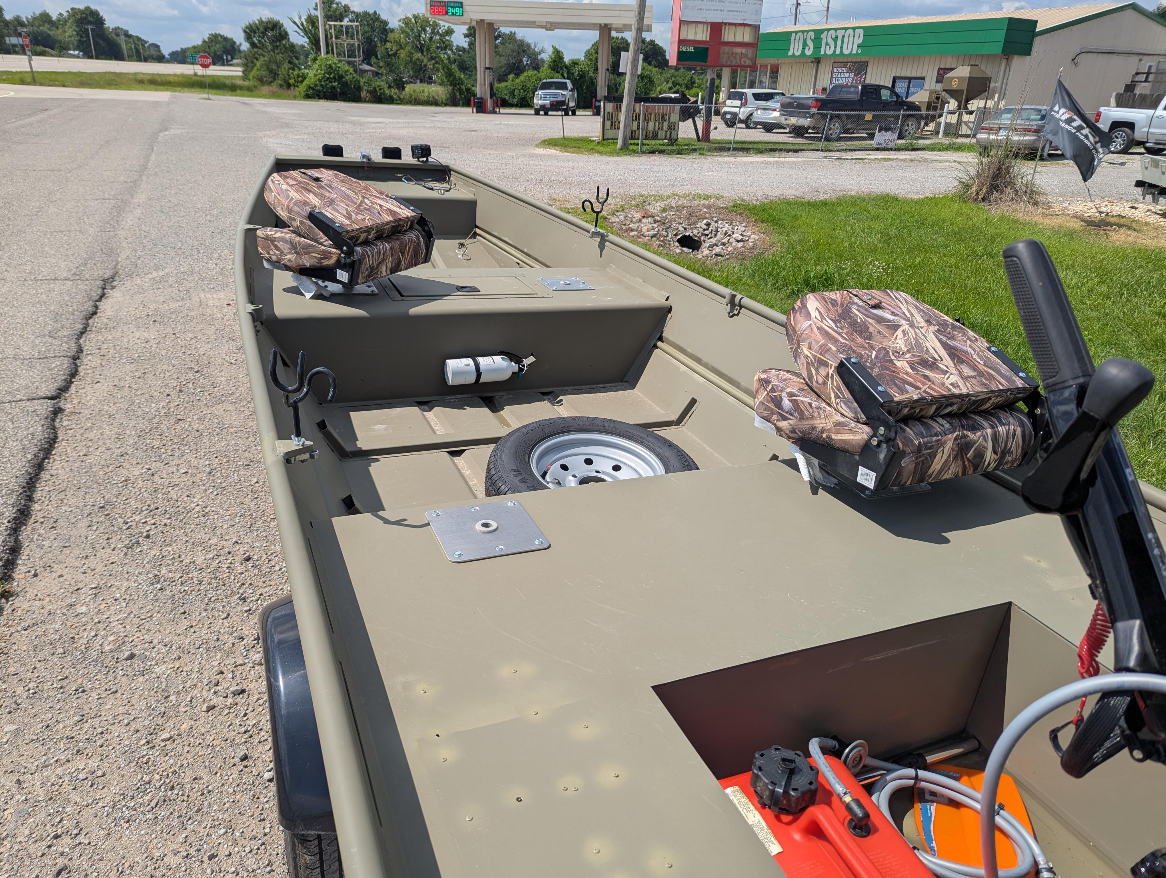 2025 Tracker Grizzly 15 Jon boat with camo seats, parked near a gas station.