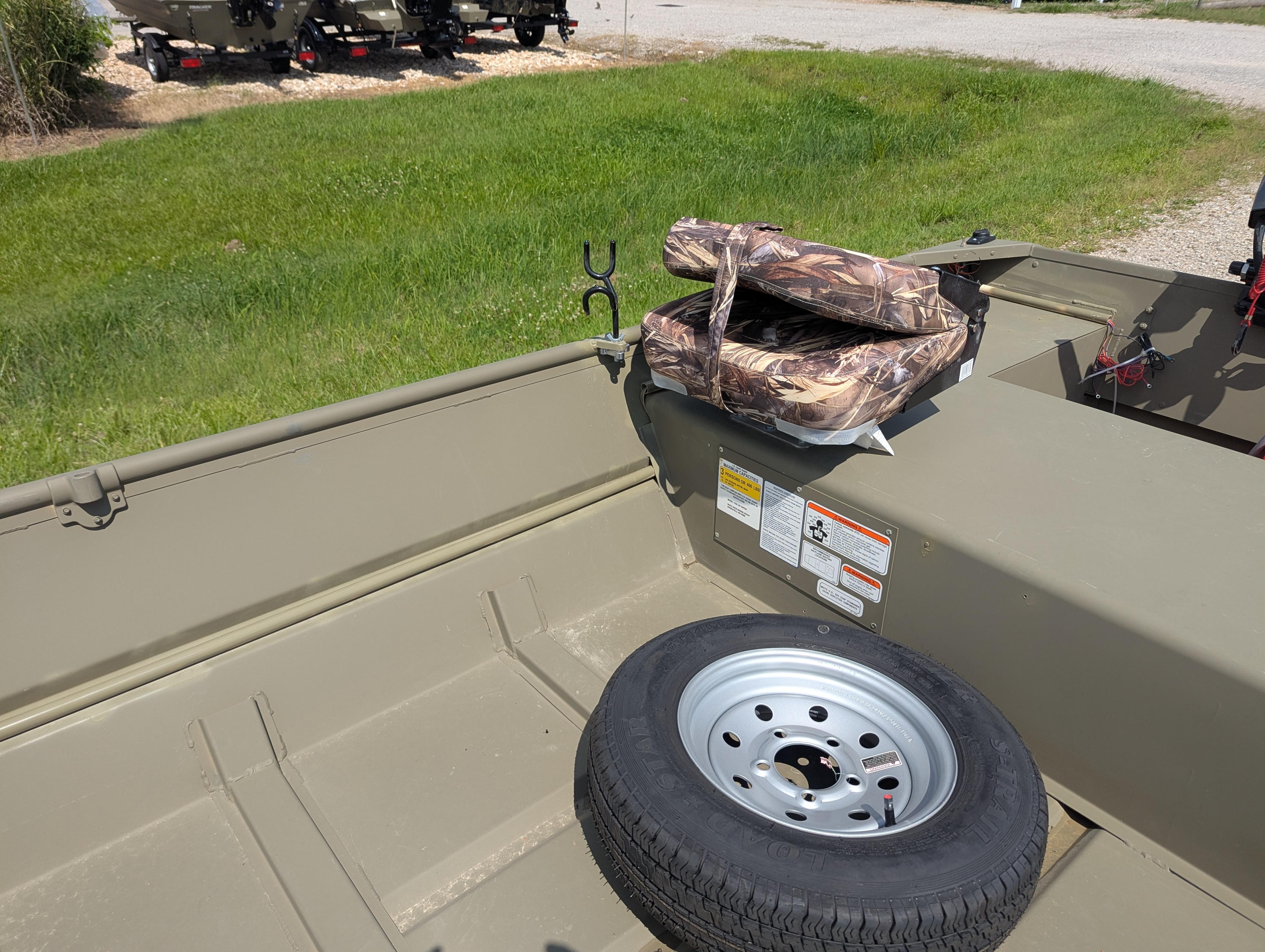 2025 Tracker Grizzly 15 Jon boat interior with spare tire and camouflage cushions.
