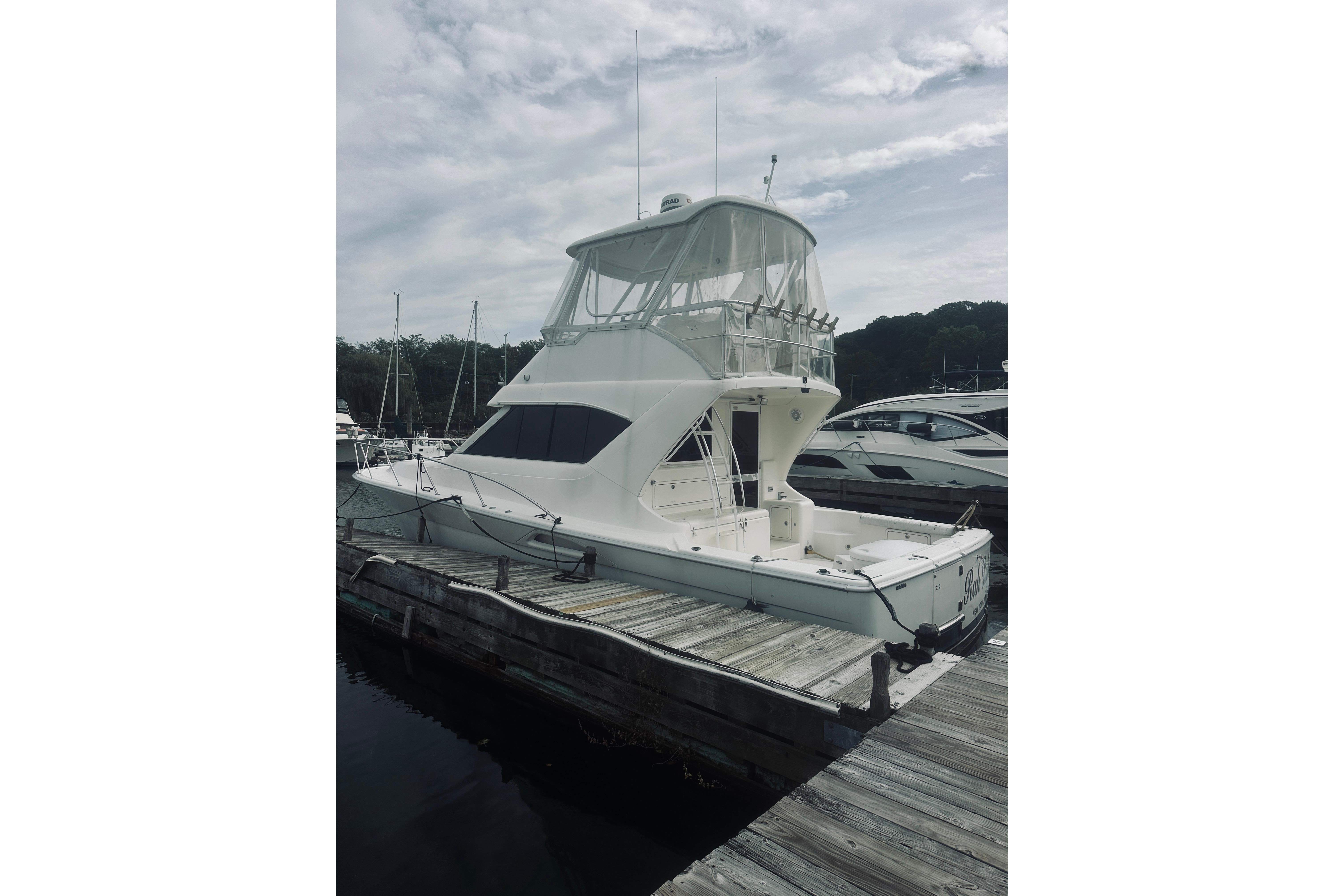 2000 Riviera 40 yacht docked at marina under cloudy sky.