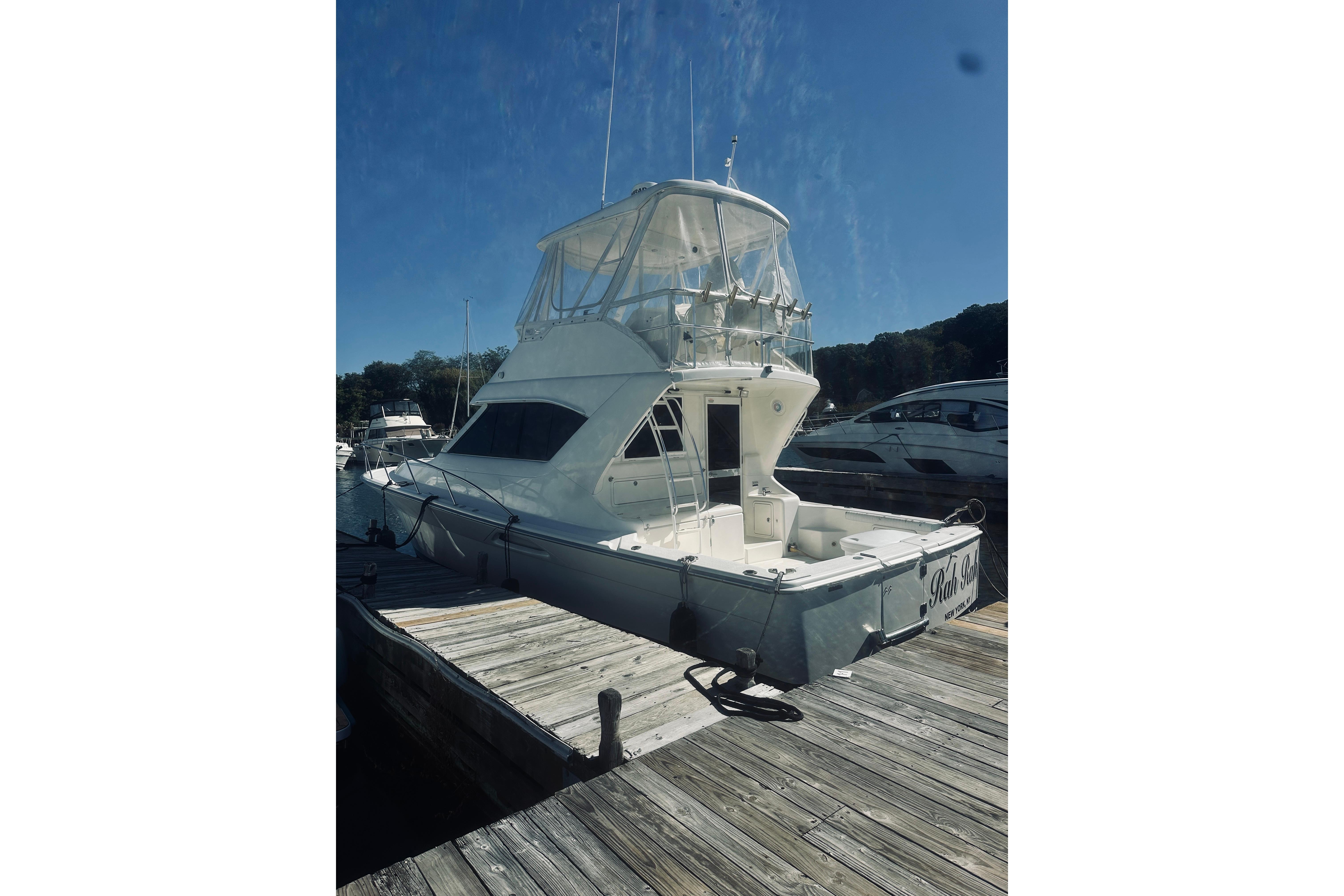 2000 Riviera 40 yacht docked at marina under clear blue sky.