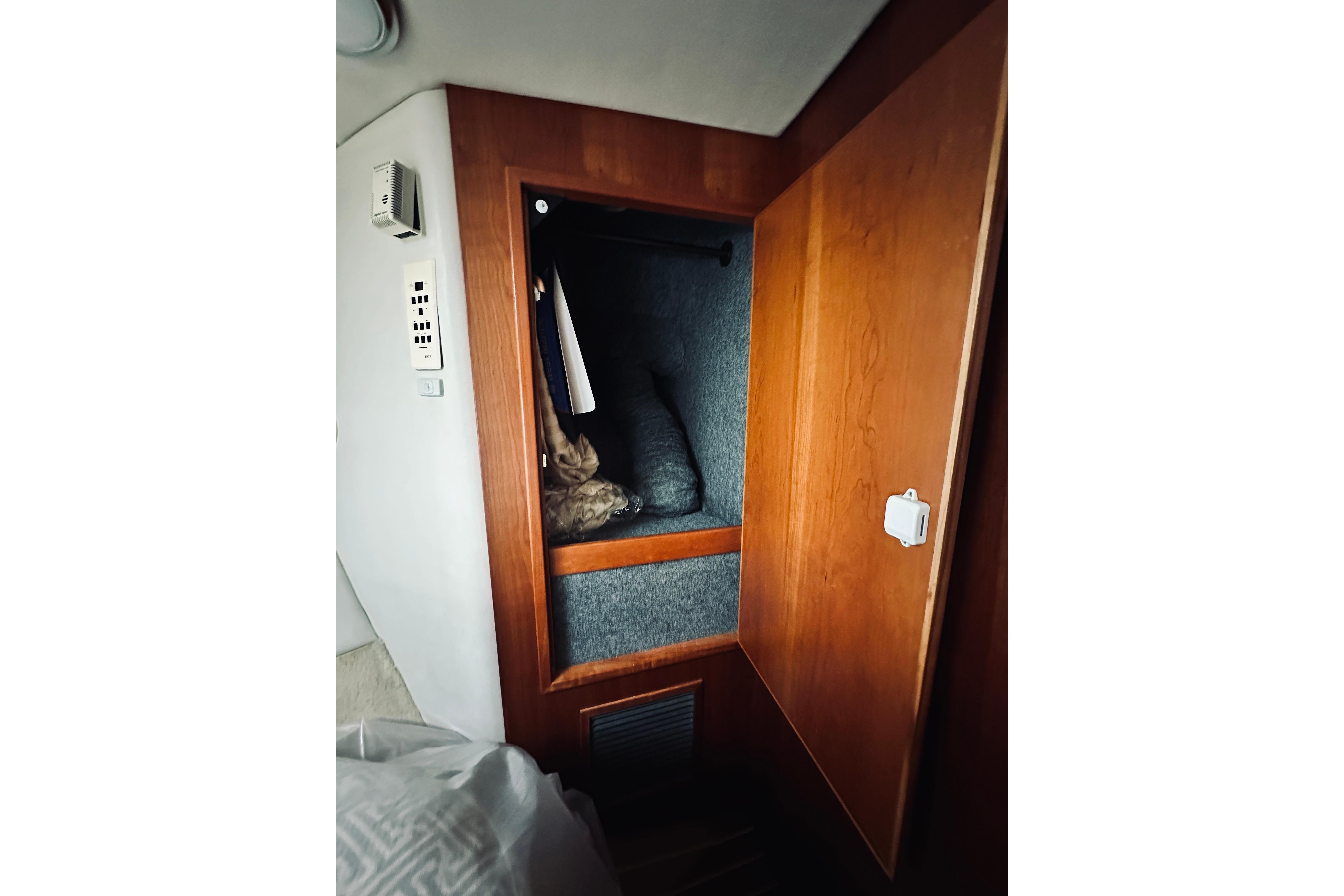 Wooden closet interior on a 2000 Riviera 40 boat, featuring hanging clothes and storage.