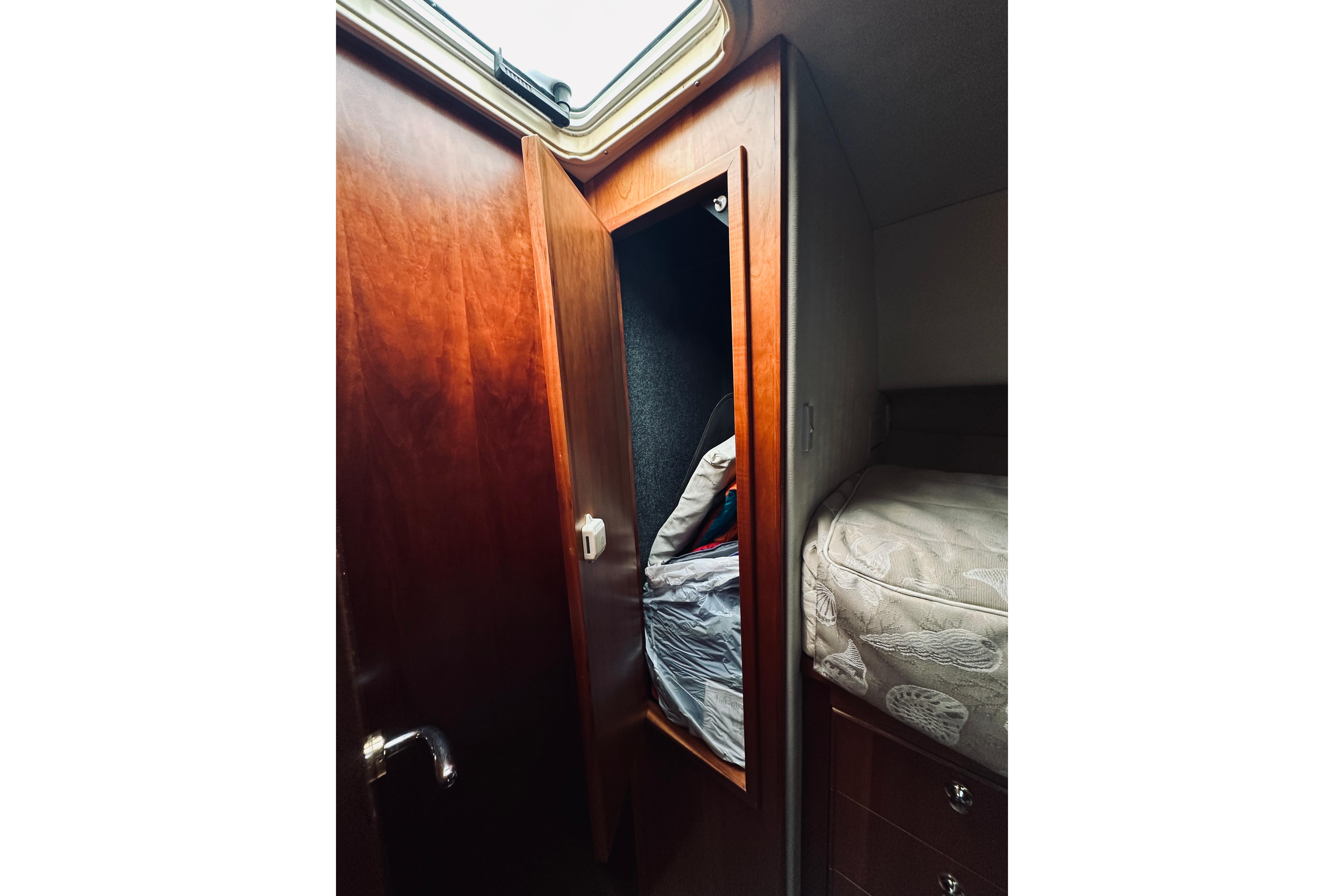 Interior of 2000 Riviera 40 yacht showing wooden cabinet and cozy bed.