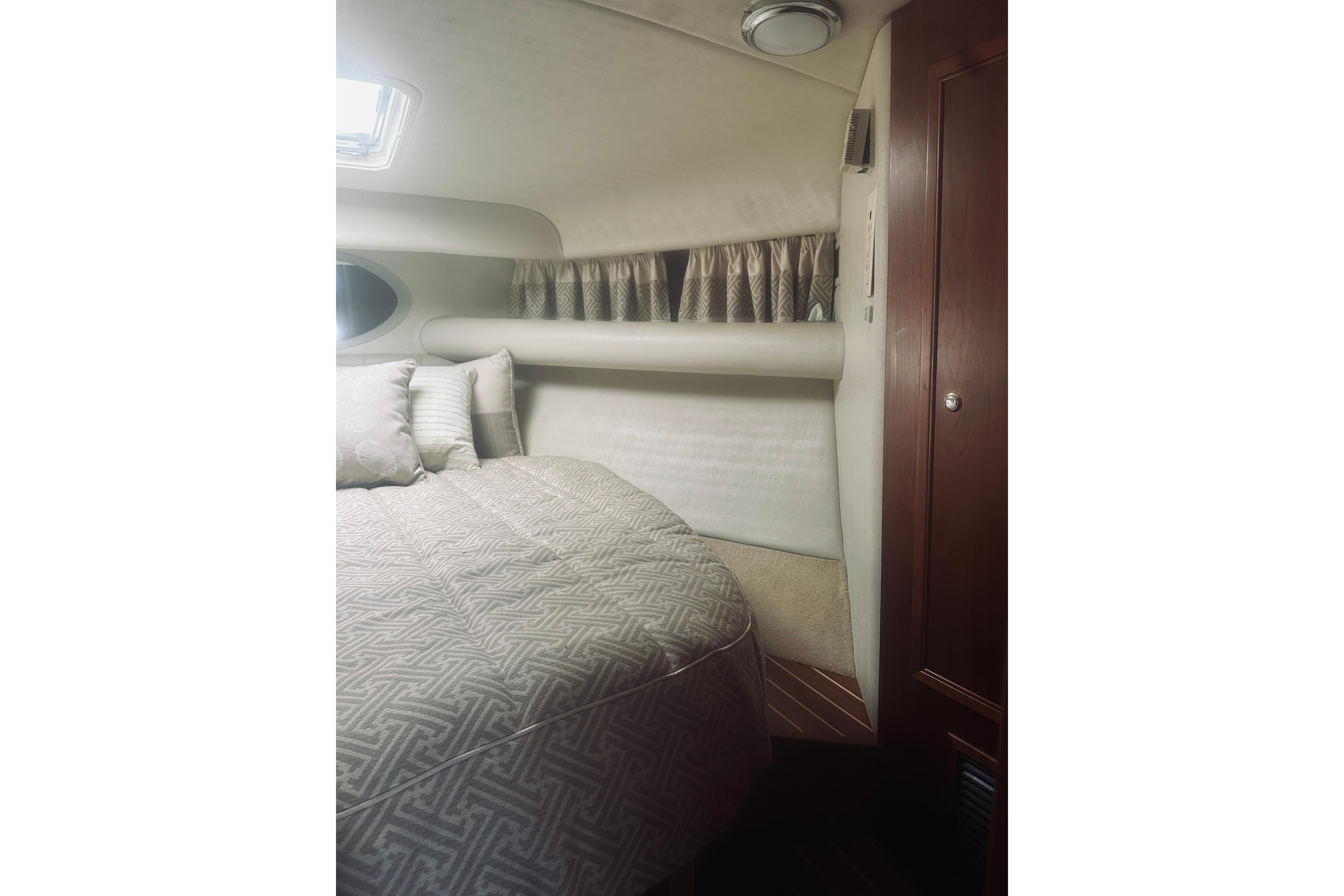 Interior of 2000 Riviera 40 yacht bedroom with bed, pillows, and wooden cabinet.